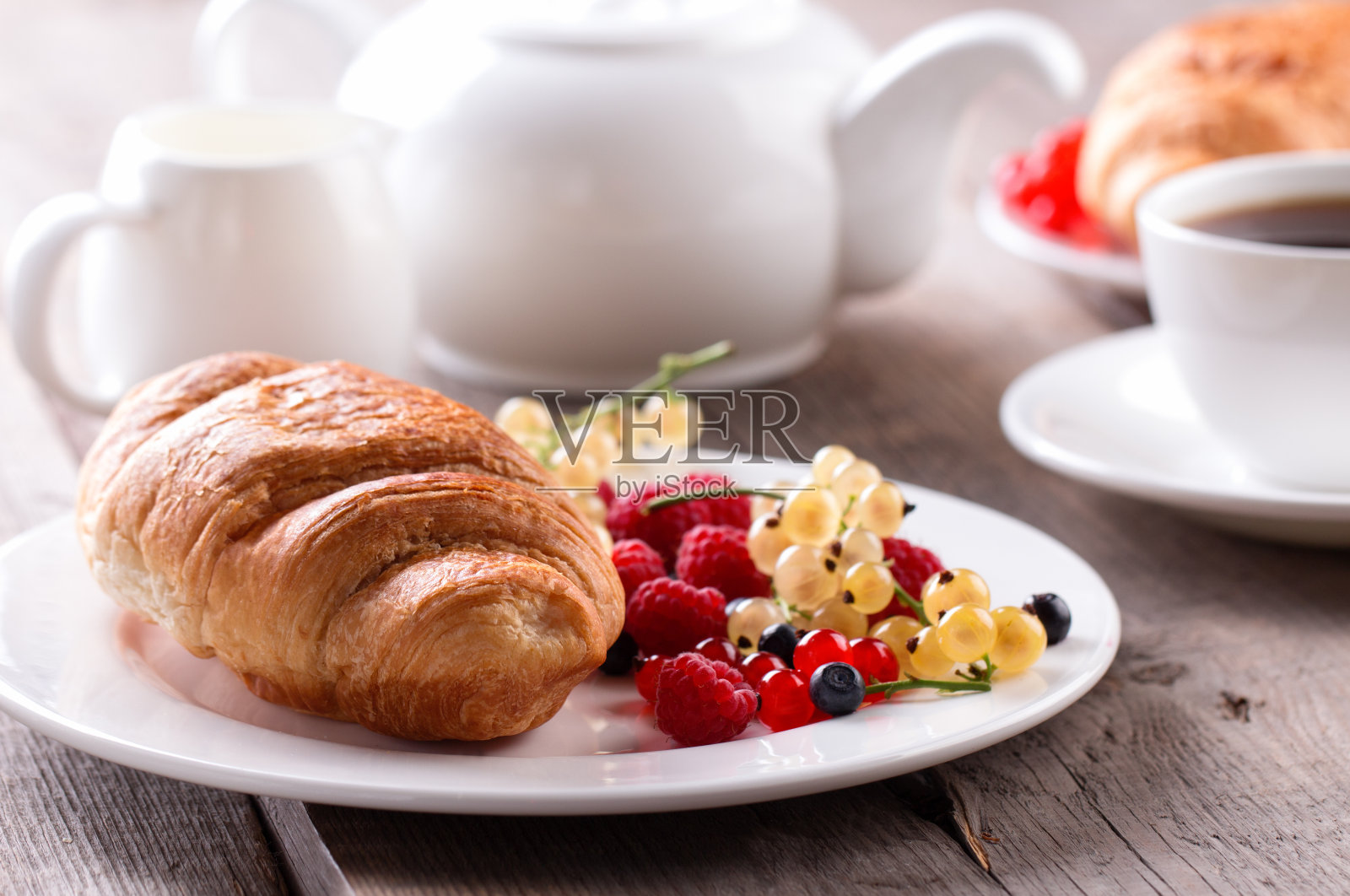 美味的早餐,新鲜的羊角面包和成熟的浆果。照片摄影图片