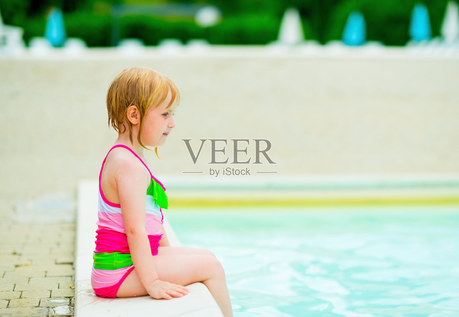 女婴坐在游泳池旁边照片摄影图片