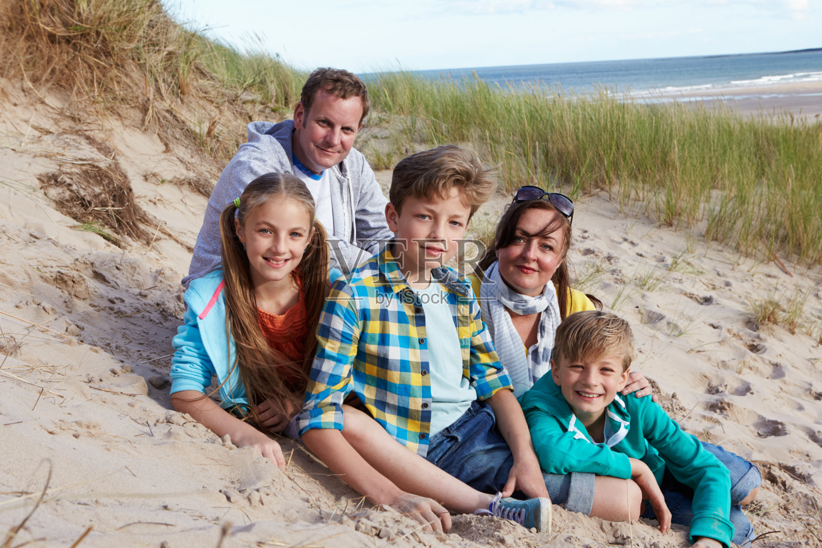 父母和孩子坐在海滩上的肖像照片摄影图片