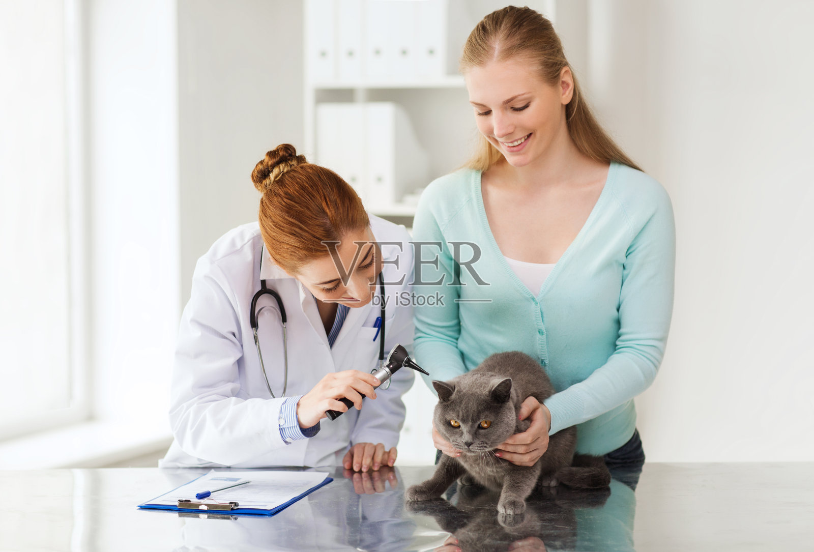 快乐的女人与猫和医生在兽医诊所照片摄影图片