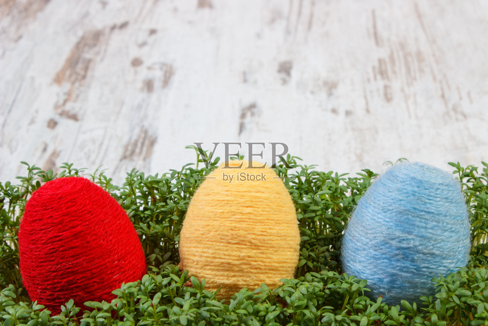 复活节彩蛋包裹羊毛线和绿色的水芹照片摄影图片