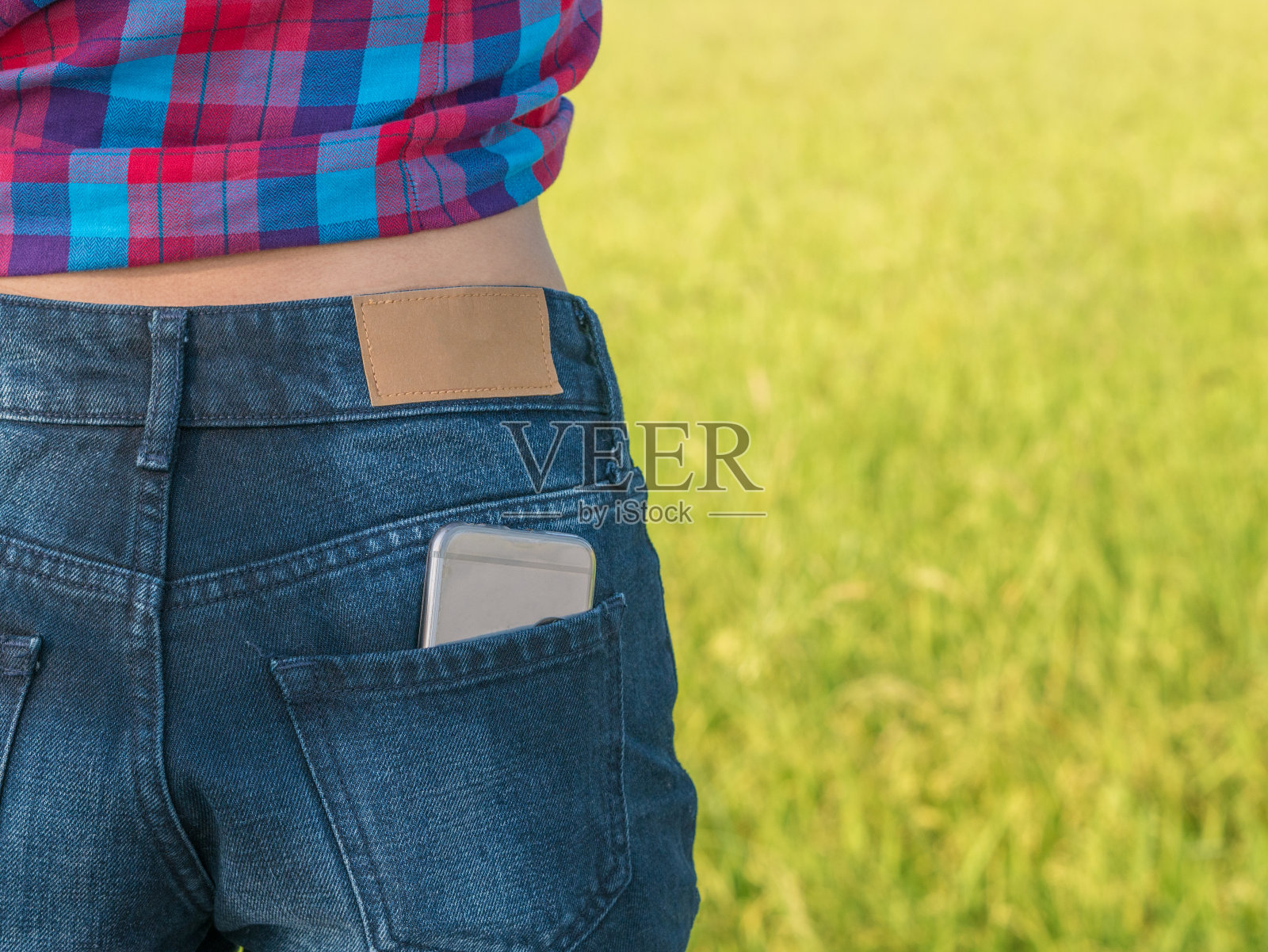户外女孩牛仔裤口袋里的手机照片摄影图片