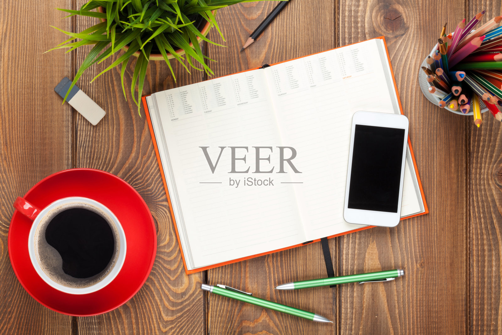 办公桌旁摆着办公用品,咖啡杯和鲜花照片摄影图片