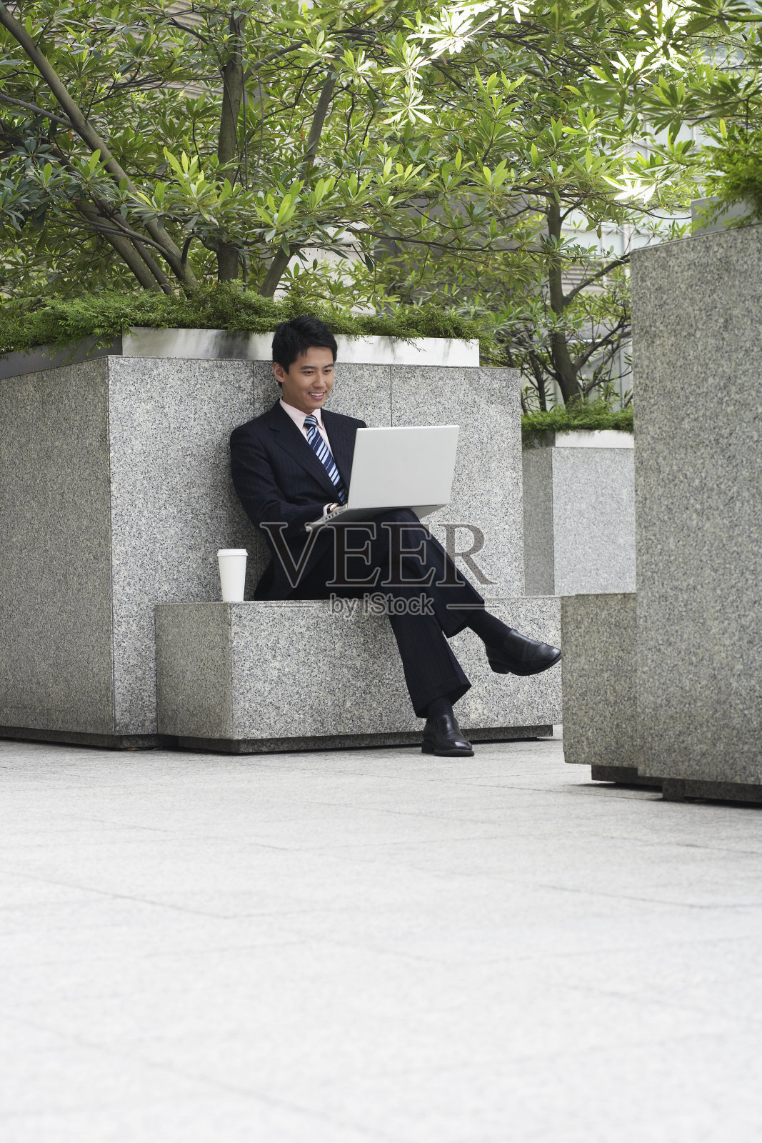 商人在石凳上使用笔记本电脑照片摄影图片