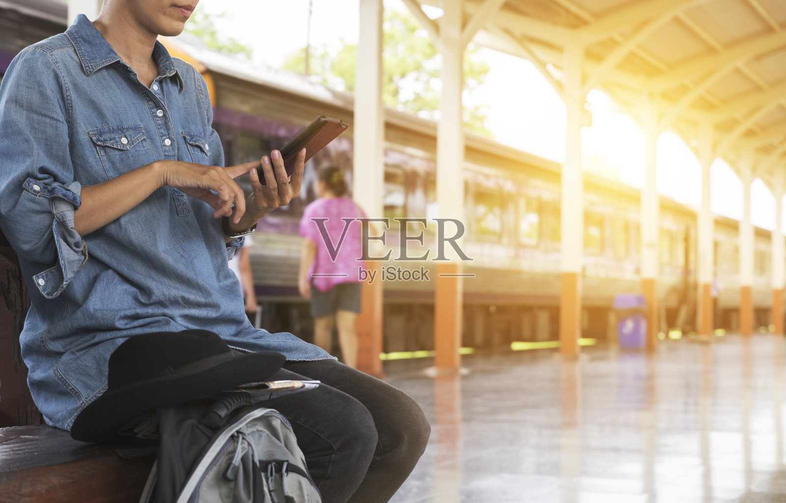 一名女子在火车站拿着智能手机背包照片摄影图片