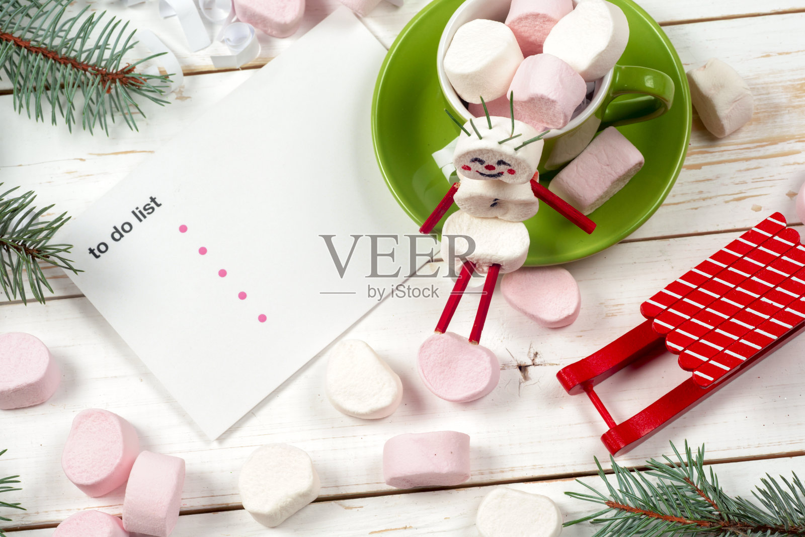 圣诞贺卡与有趣的棉花糖雪人在绿色的杯子,树照片摄影图片