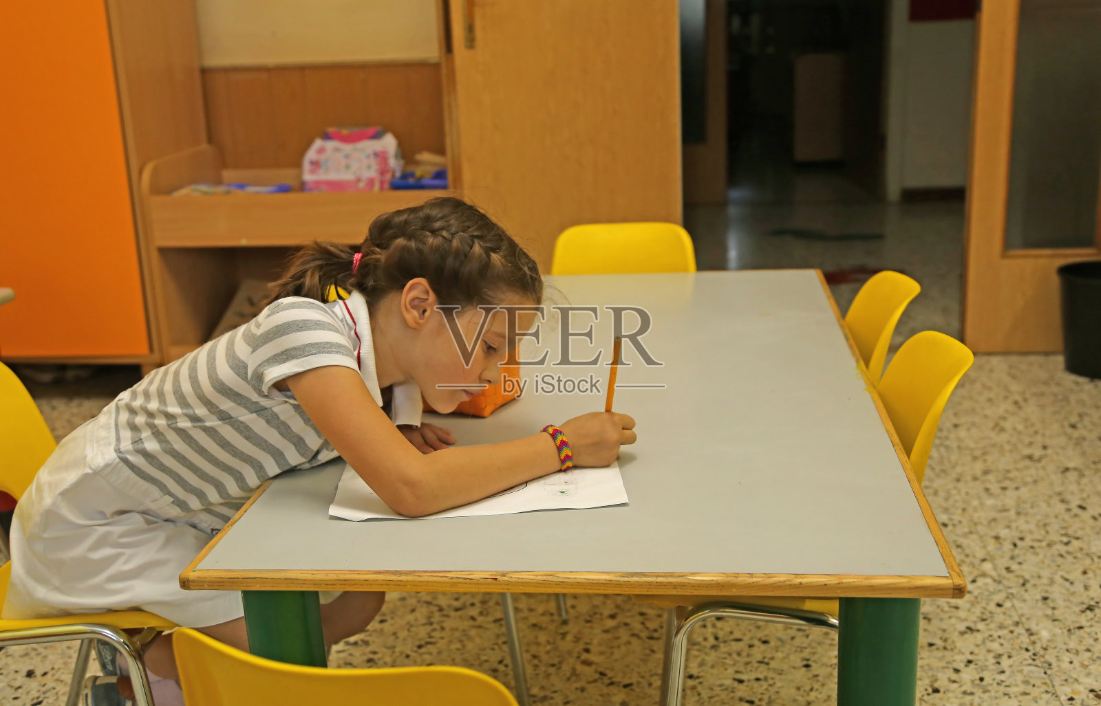 坐在黄色椅子上的小女孩在纸上写字照片摄影图片