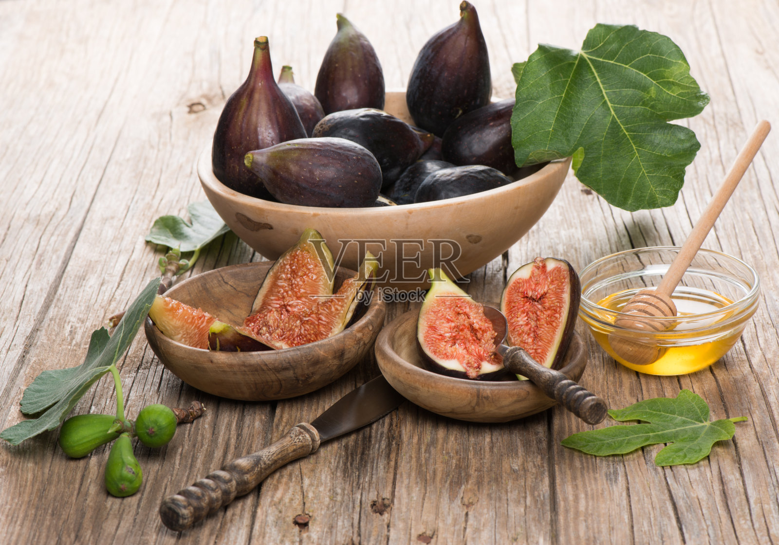 碗里盛着成熟的无花果,木桌上放着蜂蜜照片摄影图片