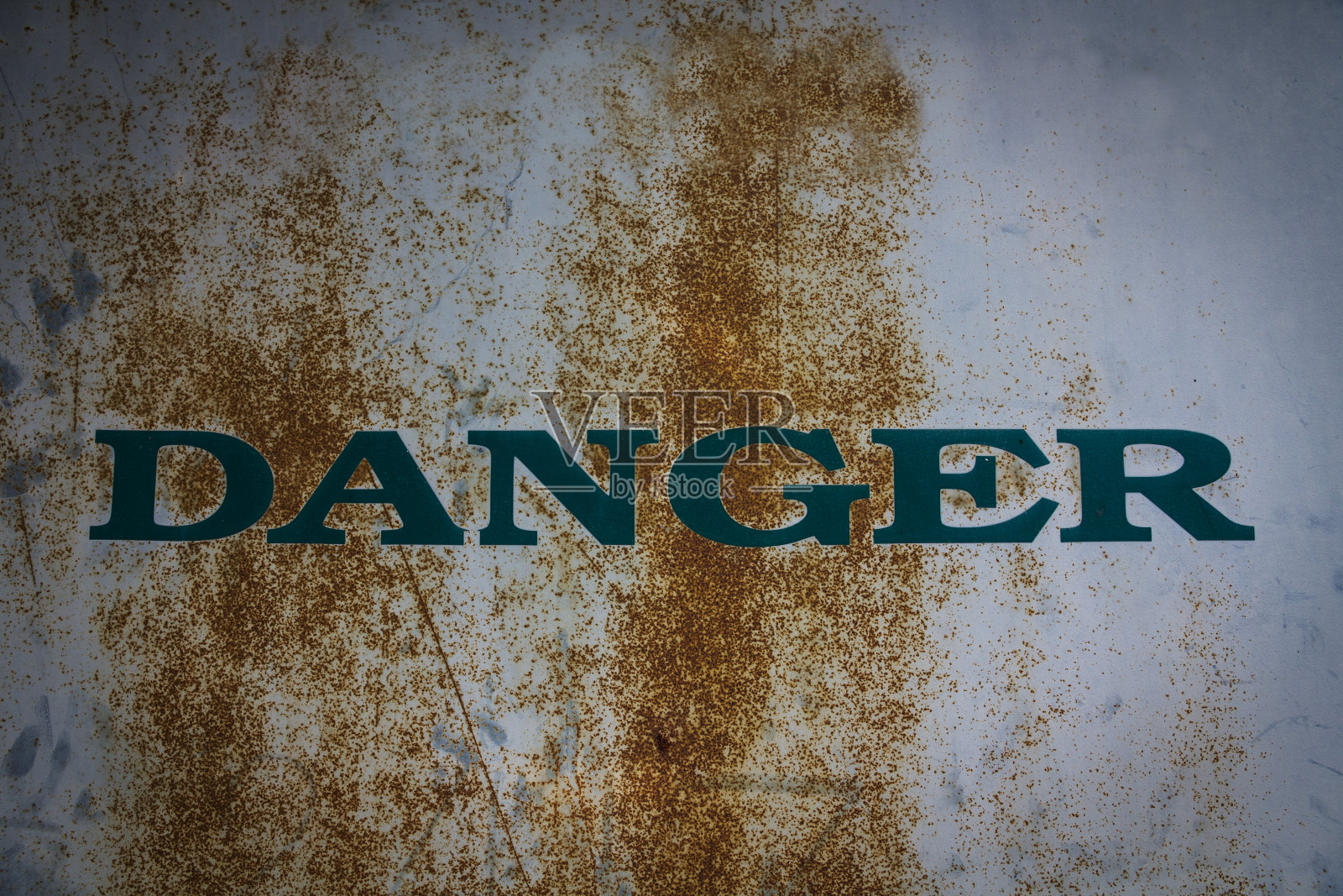 锈迹斑斑的金属墙壁上的危险警告。照片摄影图片