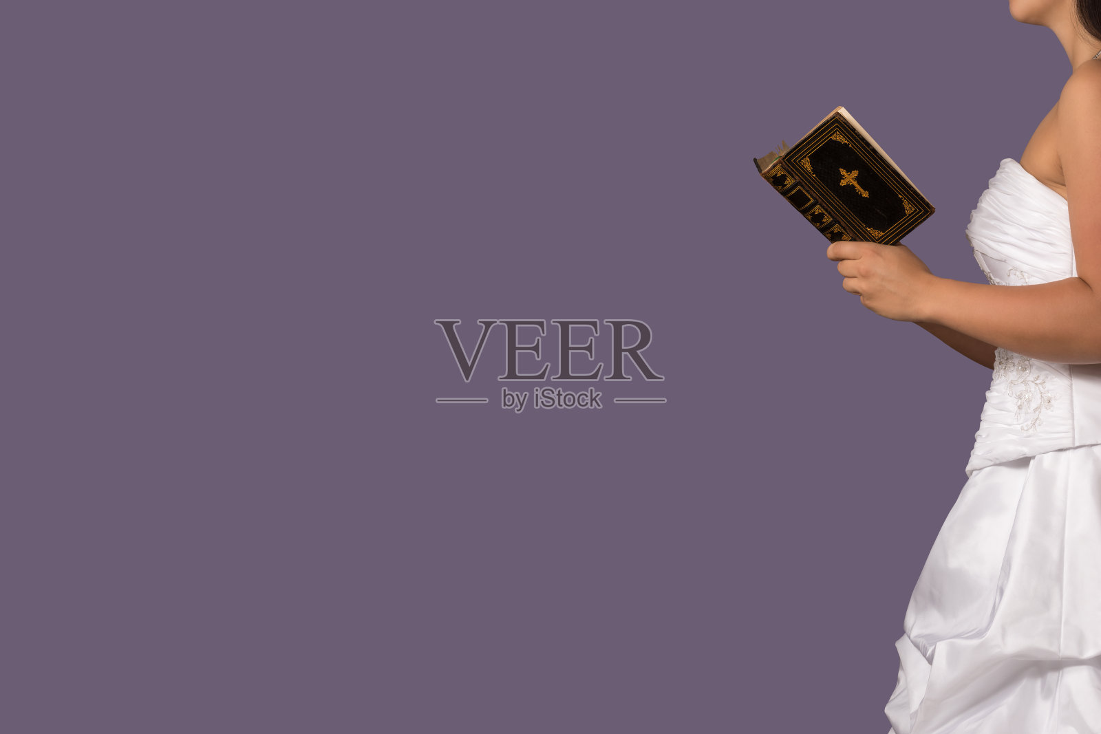 年轻的新娘穿着婚纱朗读《圣经》照片摄影图片