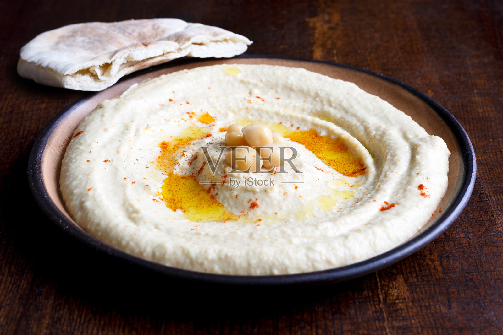 棕色陶瓷碗里的鹰嘴豆泥和皮塔饼。照片摄影图片