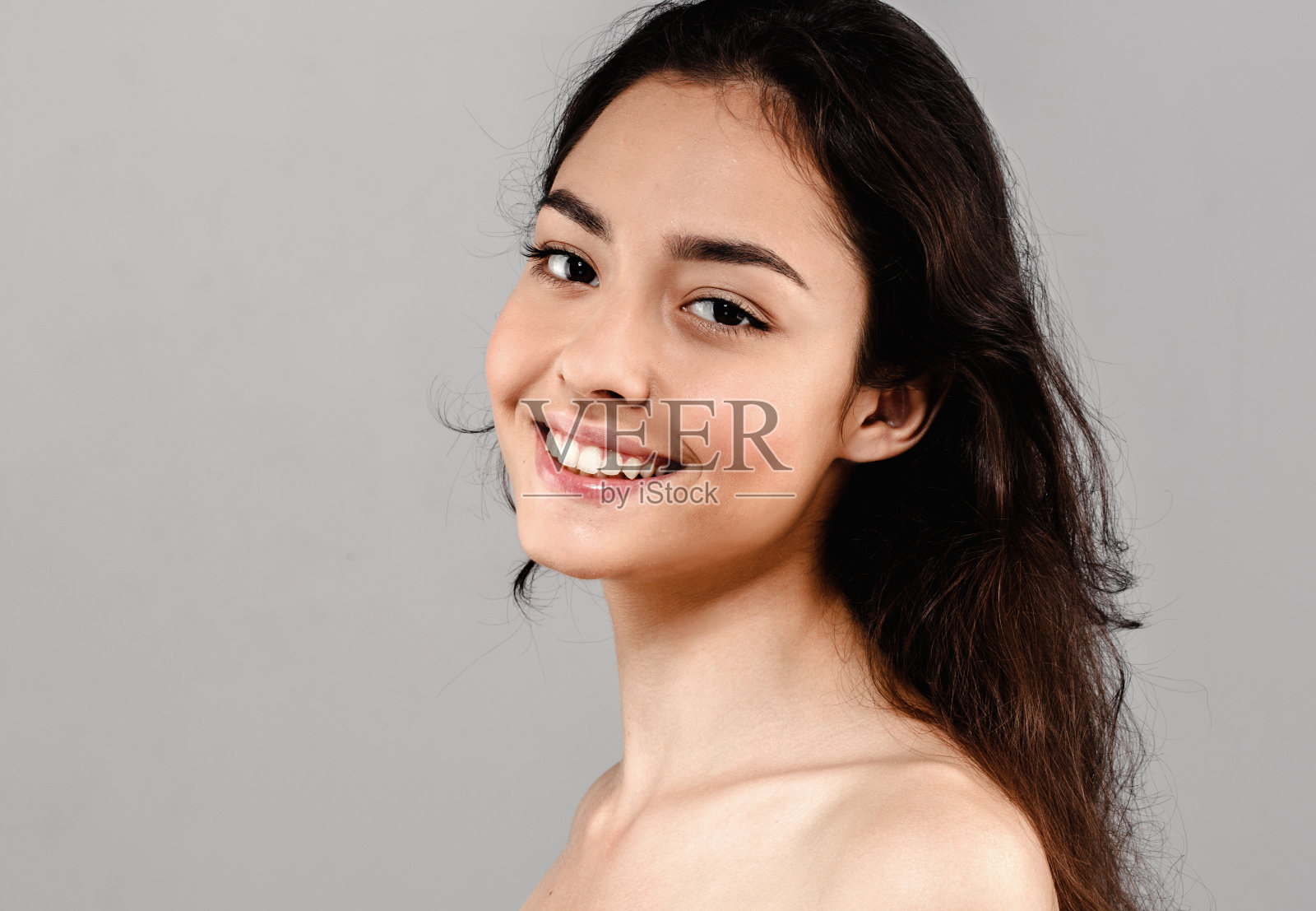 美丽的女人脸近距离肖像。灰色的背景。照片摄影图片