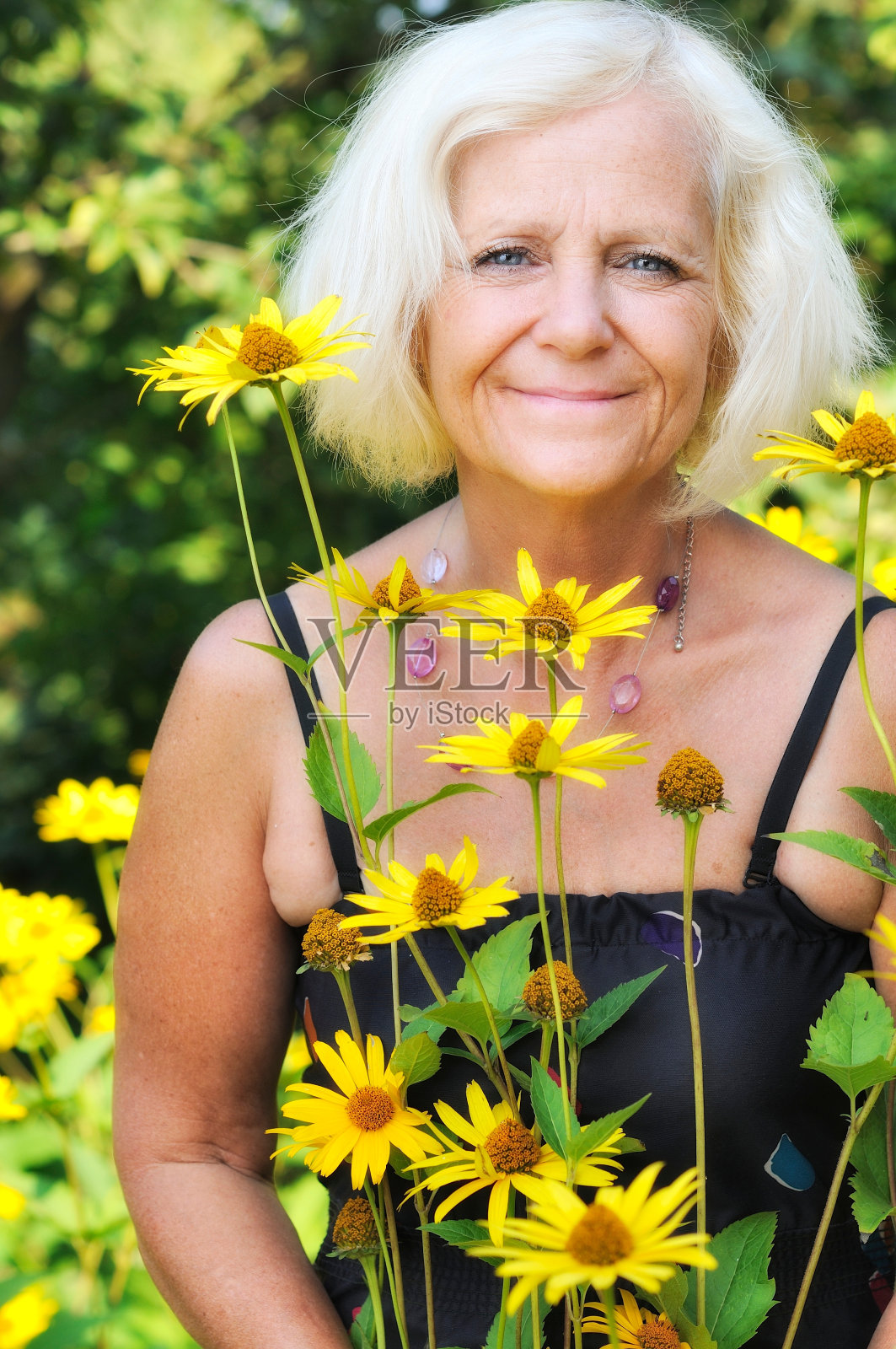 成熟的女人在花园里开满鲜花。照片摄影图片