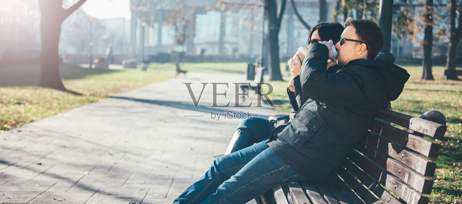 一对夫妇坐在公园长椅上喝咖啡照片摄影图片