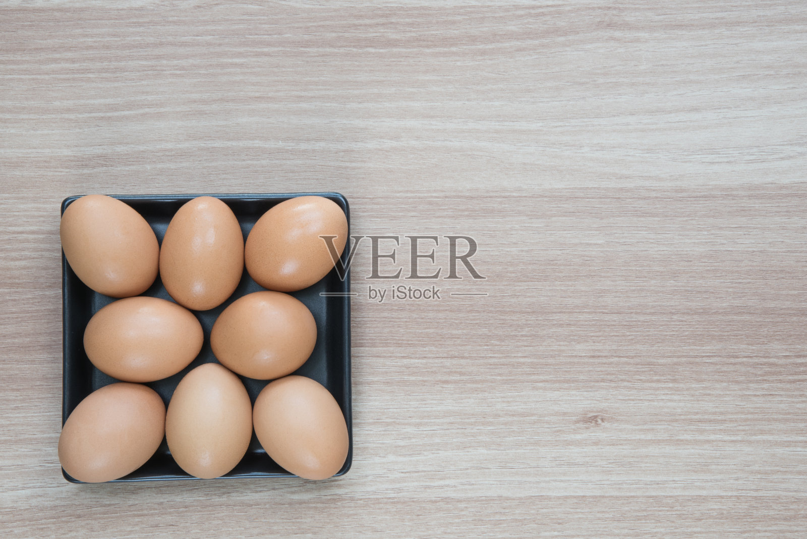 8个鸡蛋放在木表面的黑色盘子里照片摄影图片