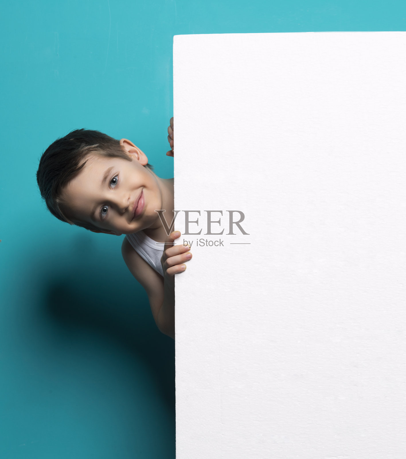 一个可爱的孩子在白色背景的黑板后面照片摄影图片