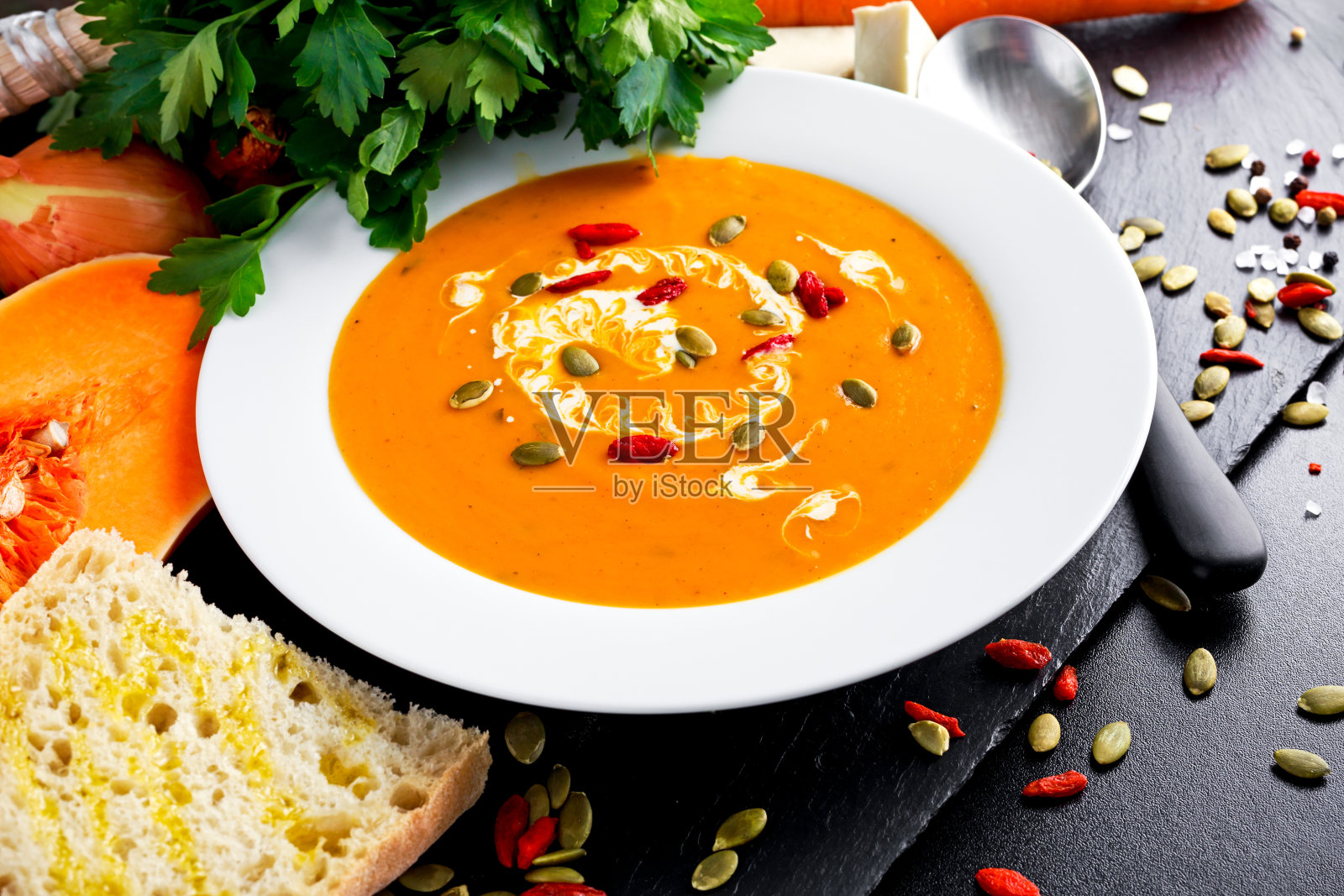 奶油胡桃南瓜和胡萝卜浓汤,配南瓜籽照片摄影图片