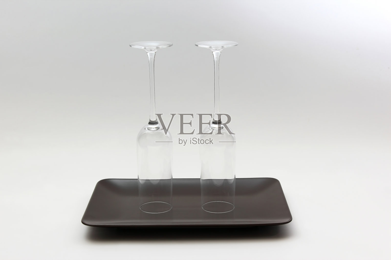 棕色盘子上放着两个倒过来的空酒杯照片摄影图片