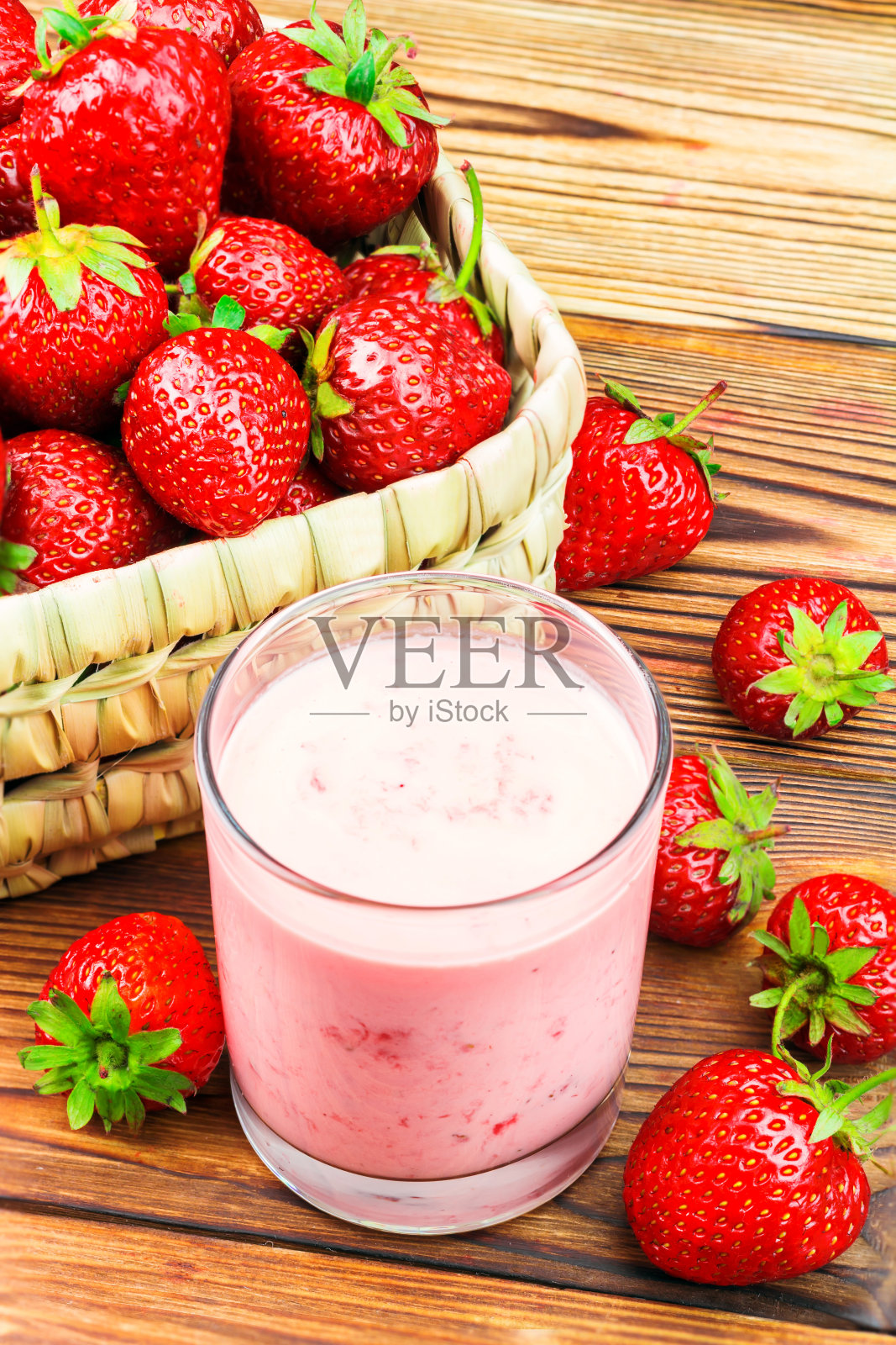 木桌上放着一杯草莓酸奶和成熟的草莓照片摄影图片