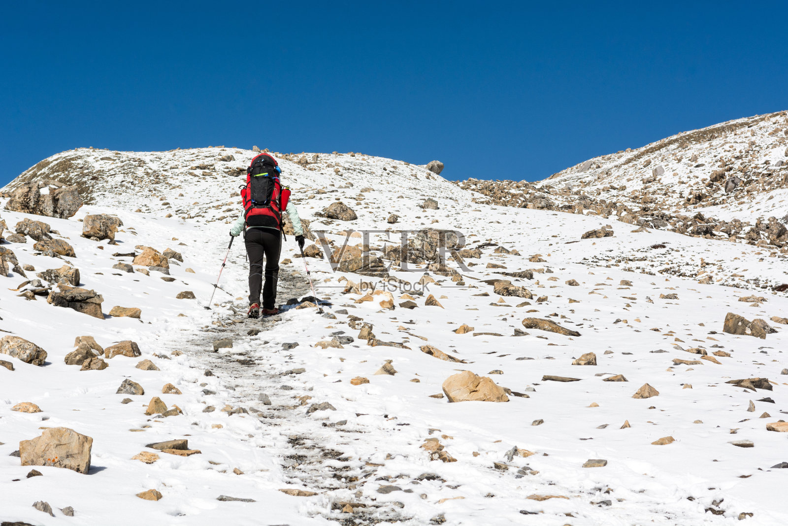女性徒步在雪山景观。照片摄影图片