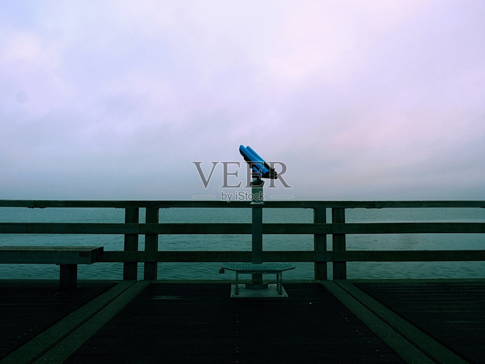 废弃的海边望远镜。海上的木制码头。抑郁、黑暗的气氛。照片摄影图片