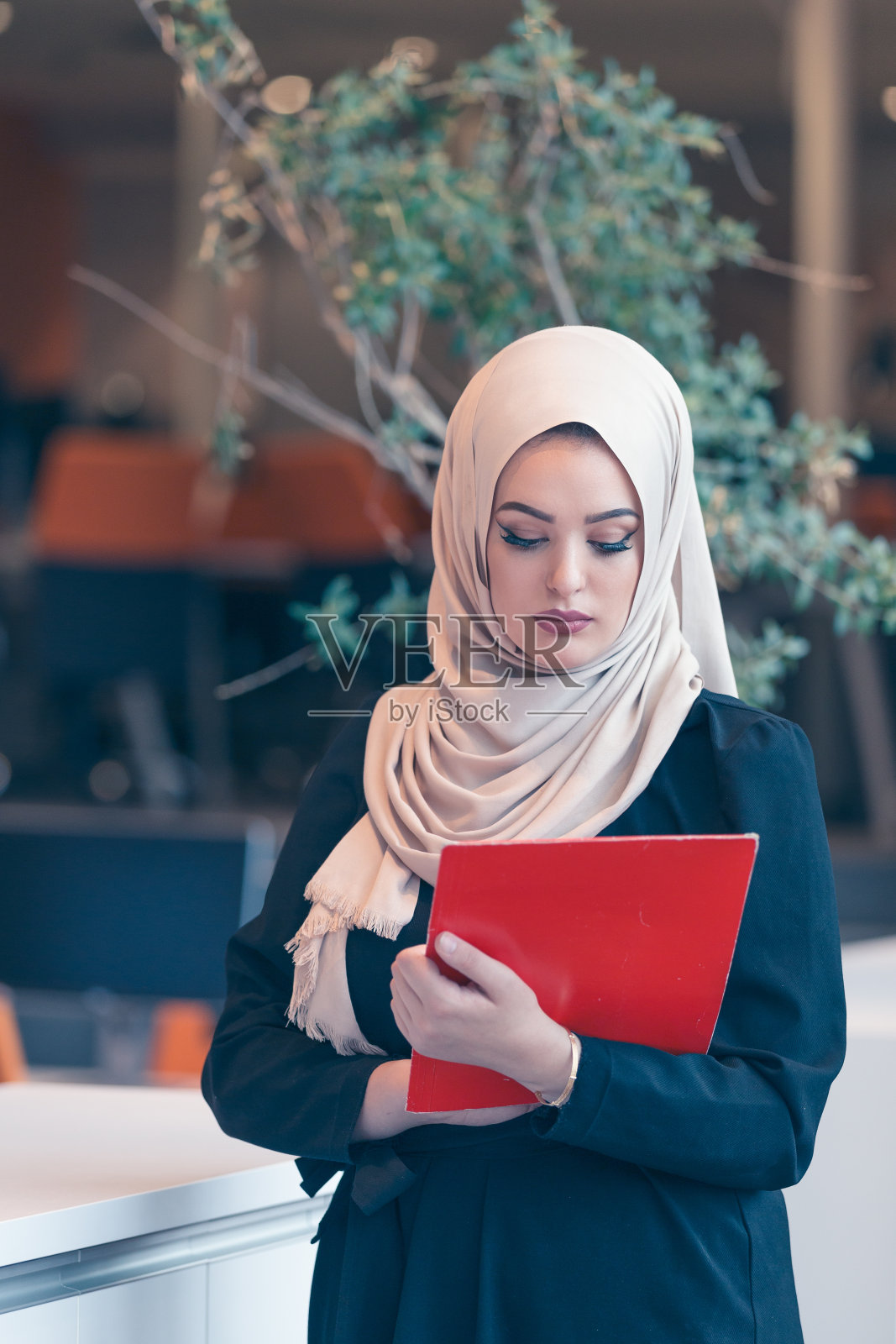 在现代创业办公室里拿着文件夹的阿拉伯女商人照片摄影图片