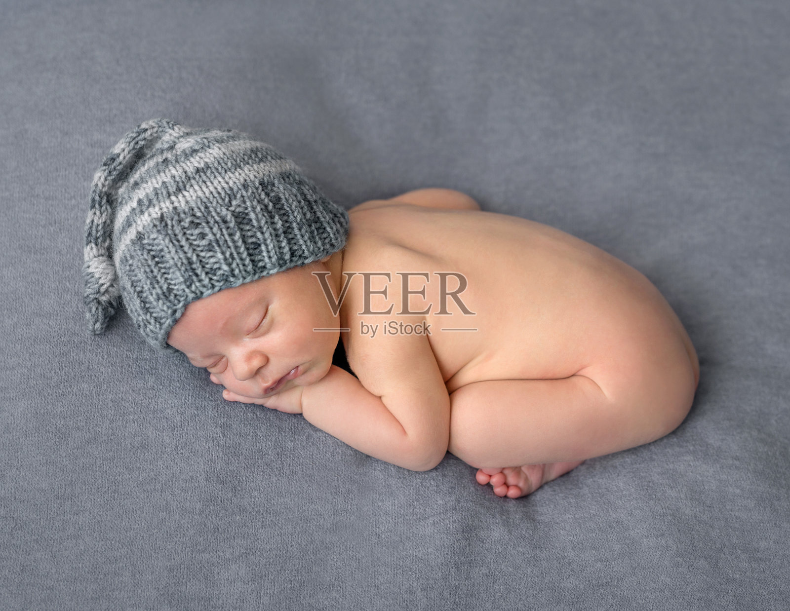 可爱的新生儿戴着帽子睡在毯子上照片摄影图片