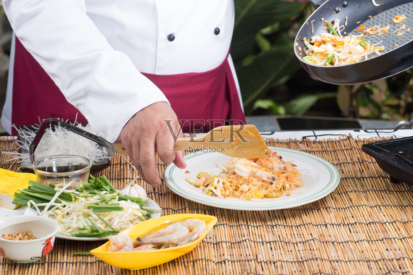 厨师把泰式炒粉放进盘子里照片摄影图片