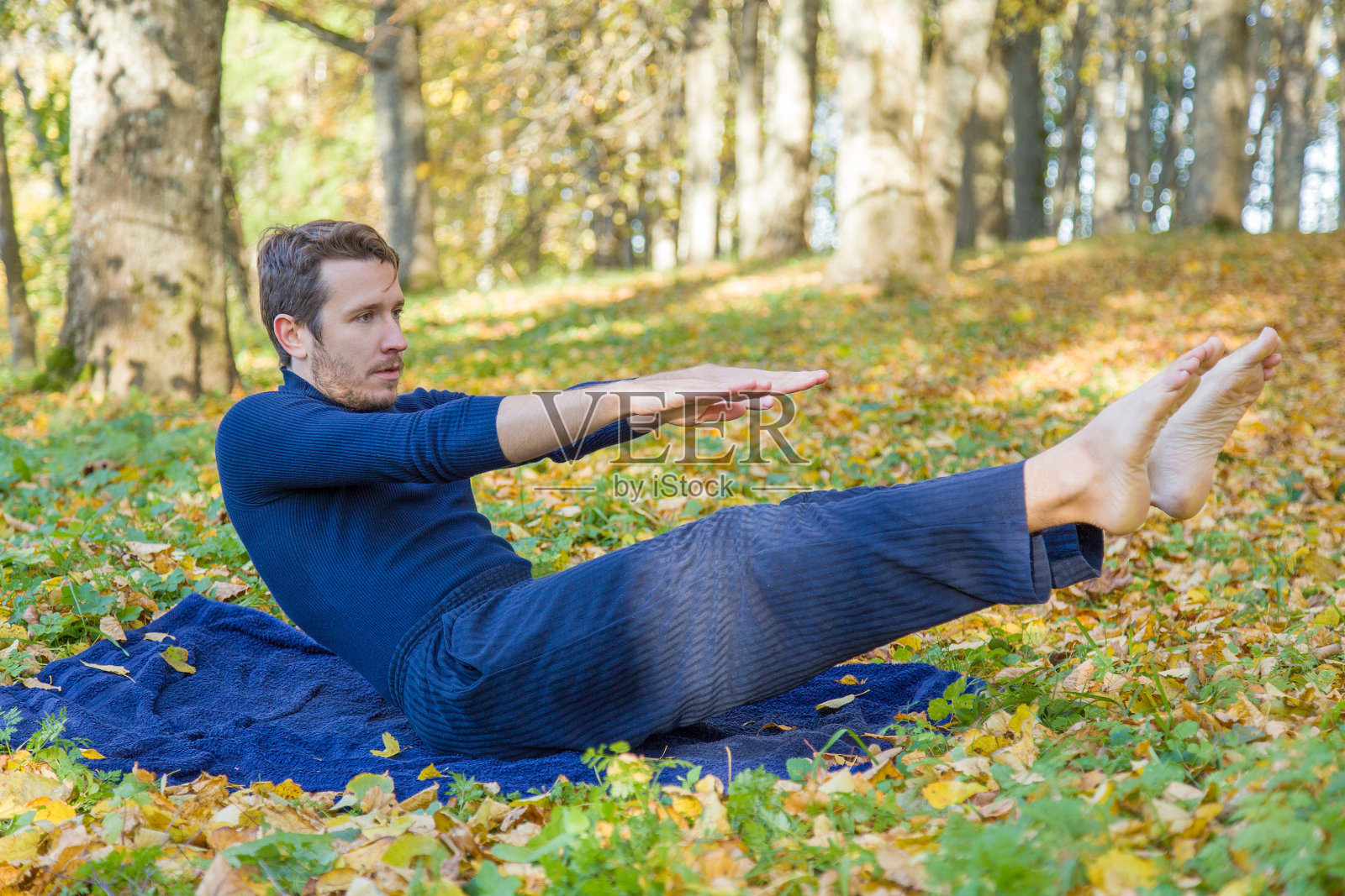 青年男子体操在公园的气氛。黄色的叶子。照片摄影图片