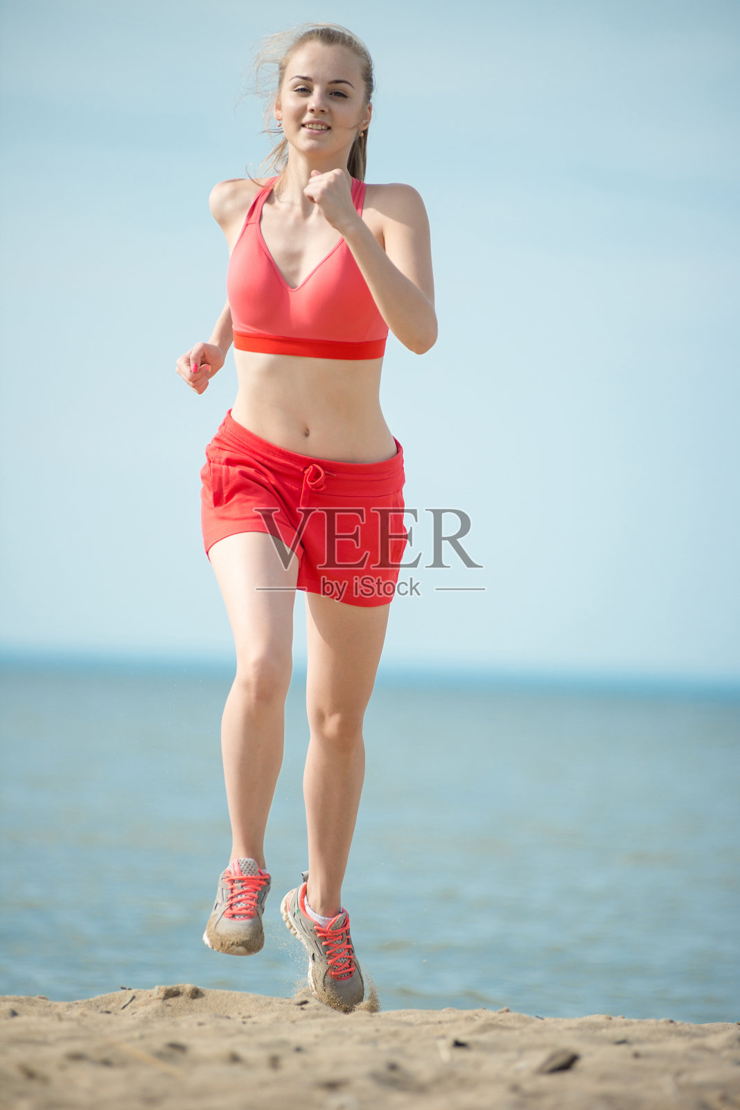年轻的女士在阳光明媚的夏日沙滩上奔跑。锻炼照片摄影图片