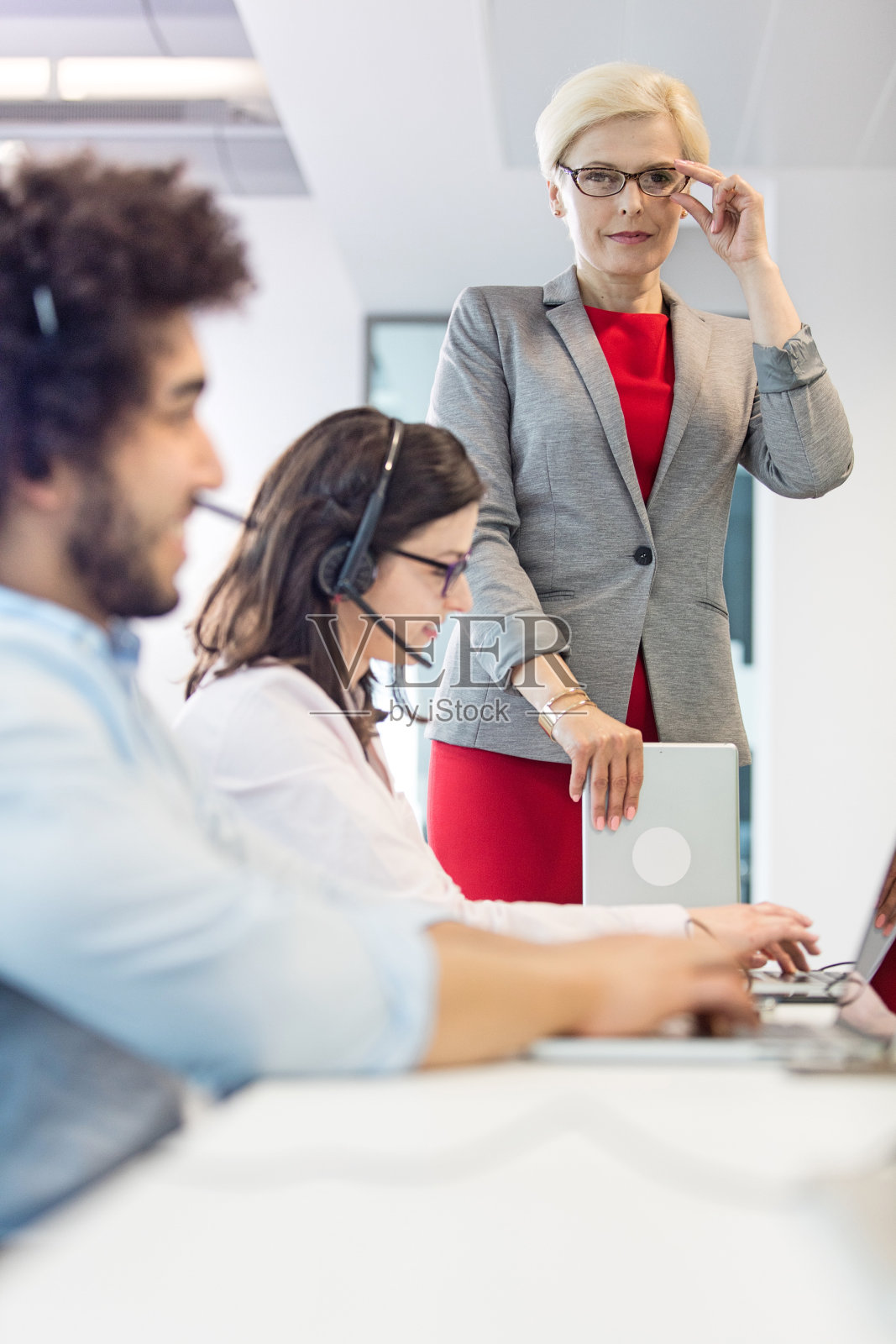 自信的中年女商人与工作中的接线员合影照片摄影图片