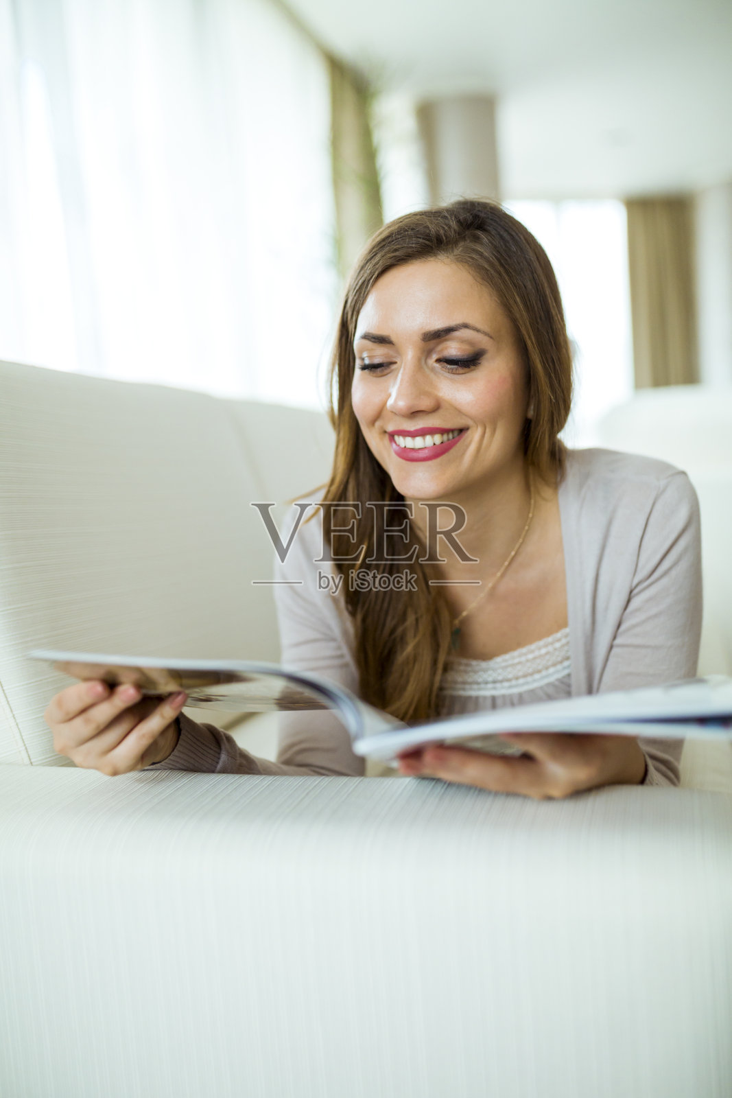 一个漂亮的女人在客厅的沙发上看书照片摄影图片