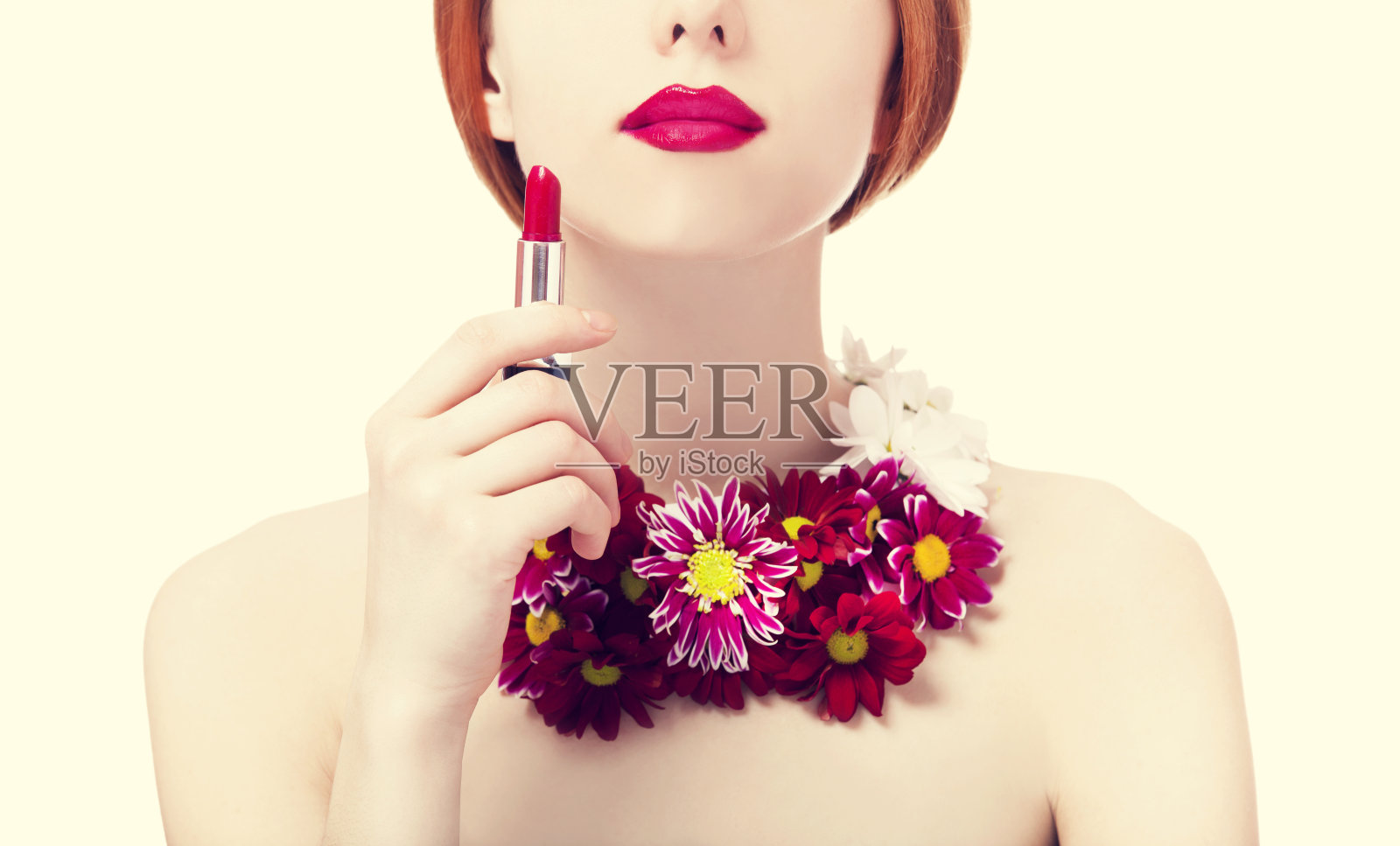 漂亮的红发女孩拿着口红,捧着花照片摄影图片
