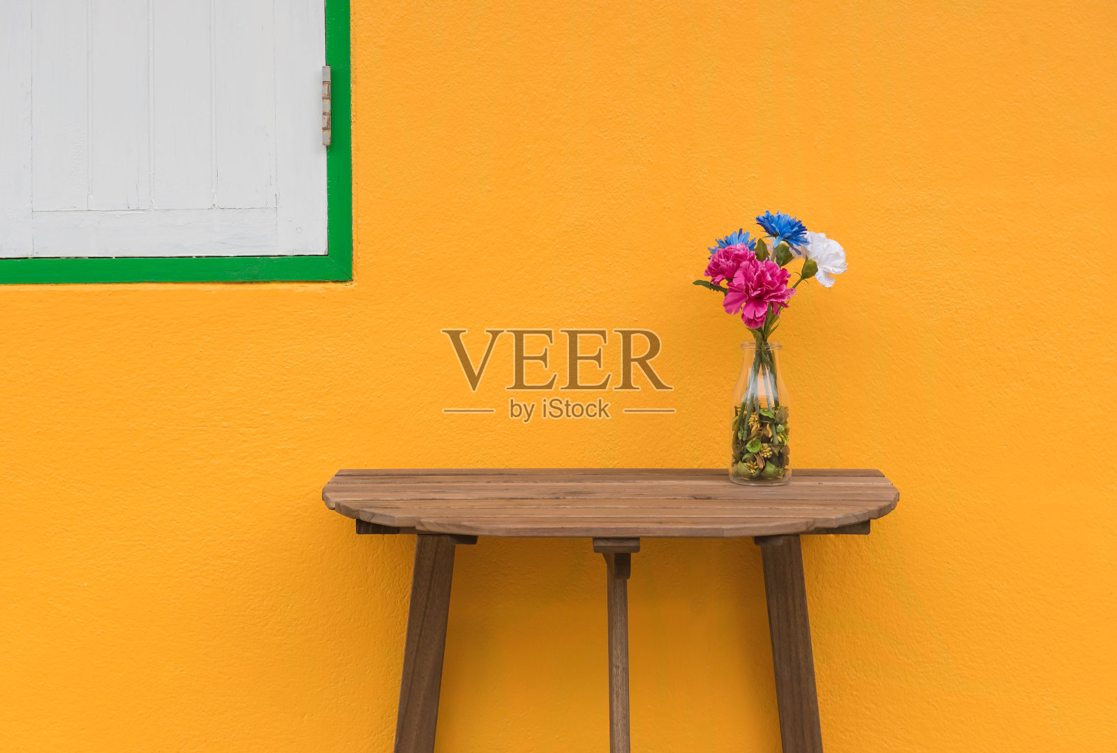 木桌上放着一盆花黄色背景。照片摄影图片