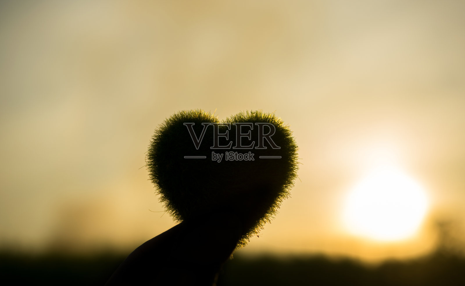 剪影绿色心与日落天空的自然背景。照片摄影图片