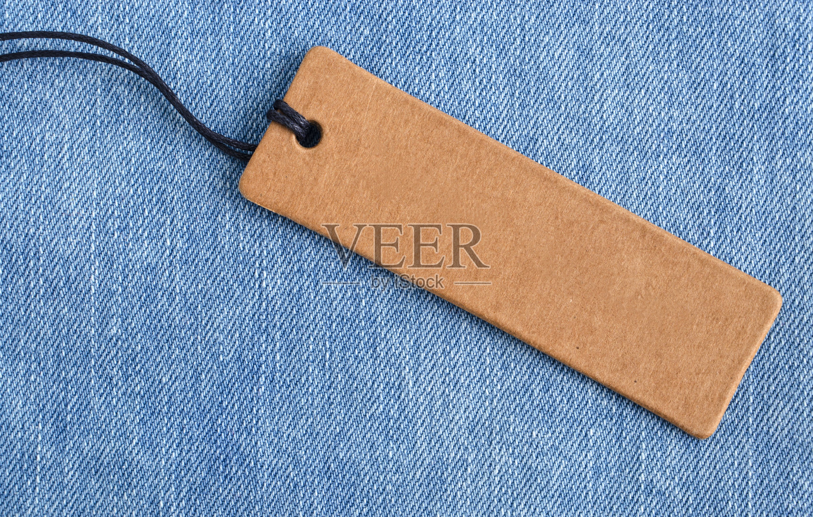 浅蓝色牛仔布上的空白纸标签。照片摄影图片