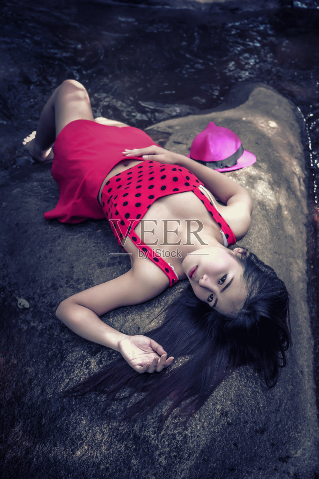 亚洲美丽年轻性感的女孩躺在一块岩石上照片摄影图片