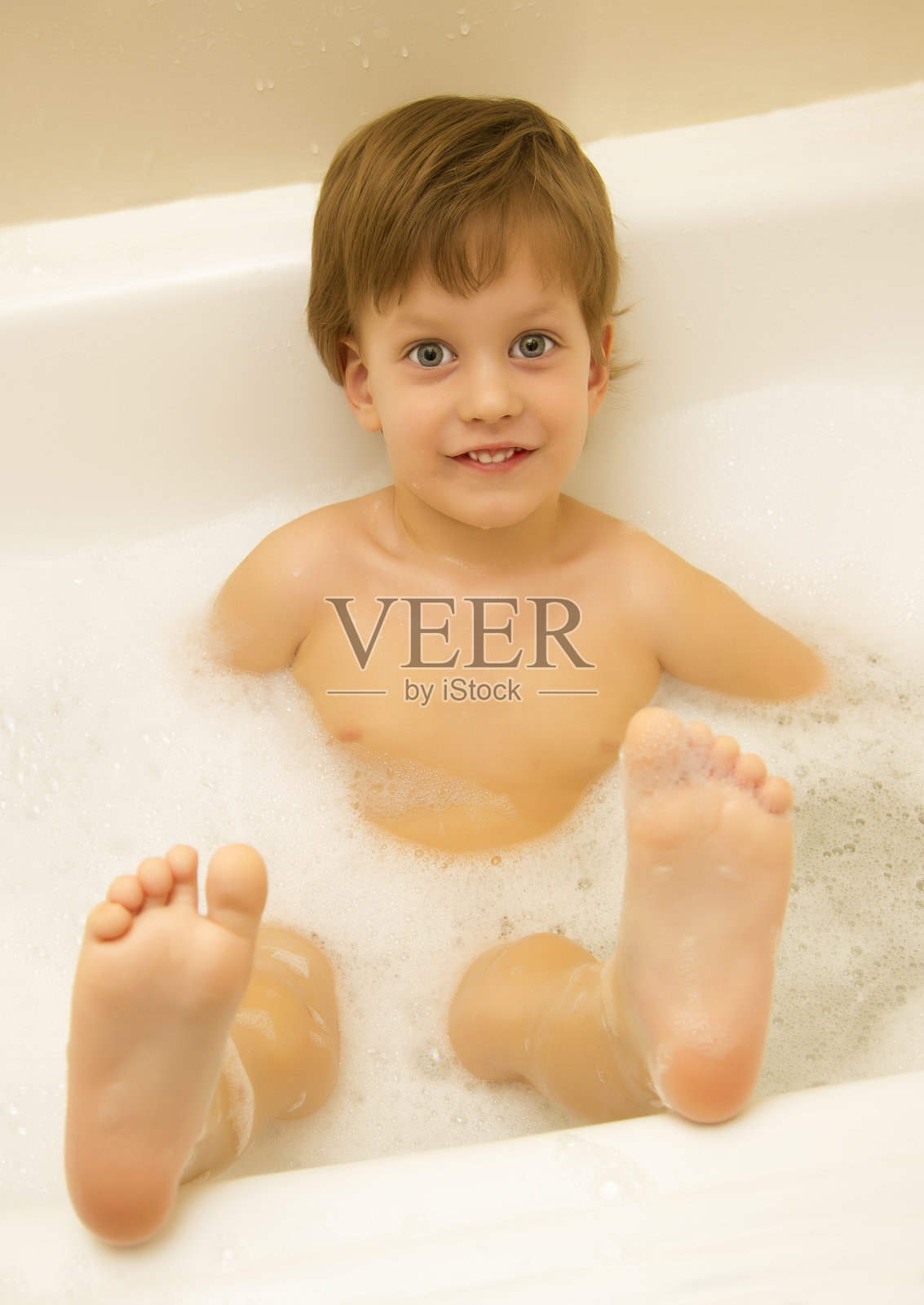 可爱的三岁男孩正在用泡沫洗澡照片摄影图片