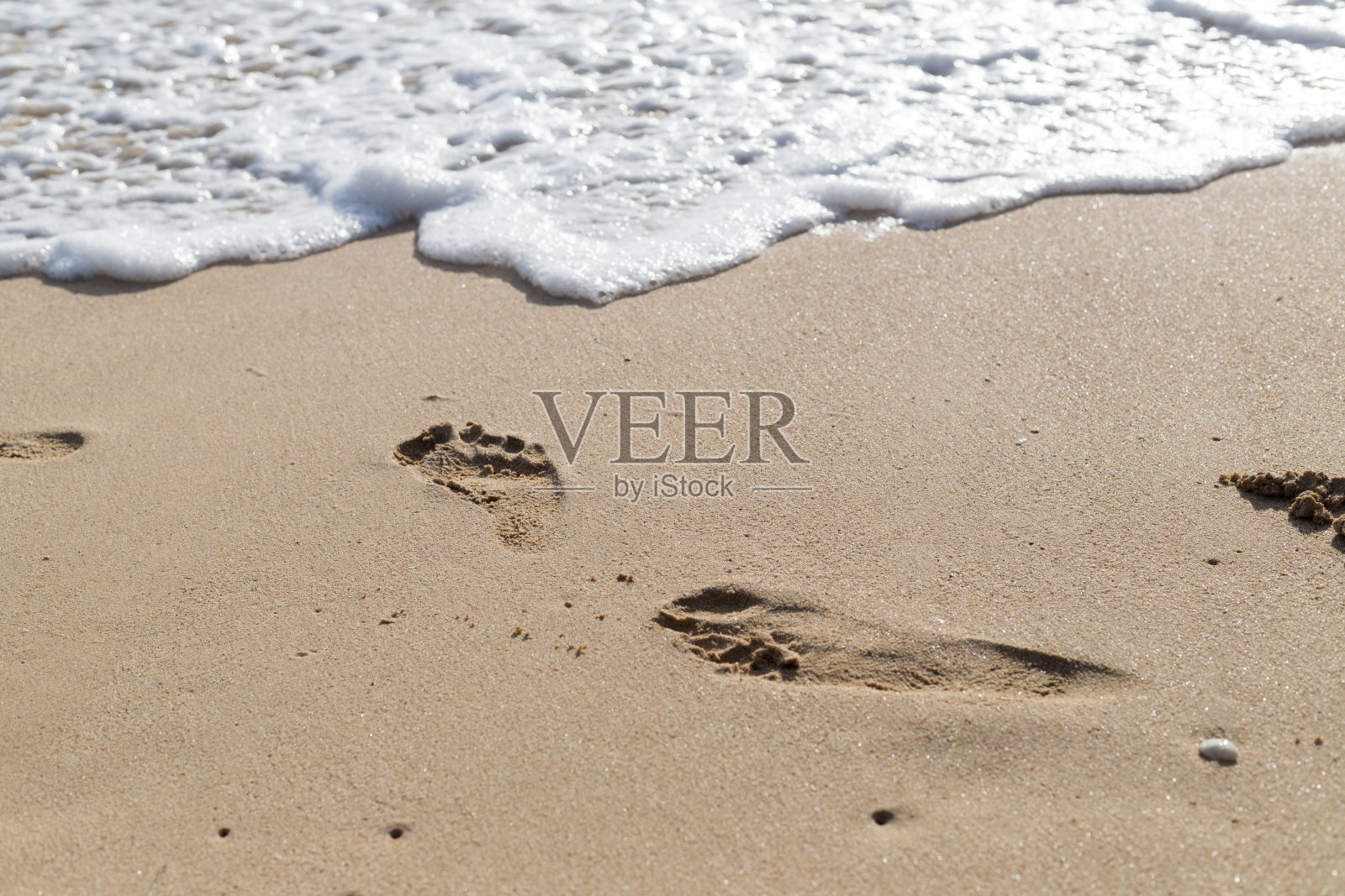 脚印在湿沙上,人在海滩上行走照片摄影图片