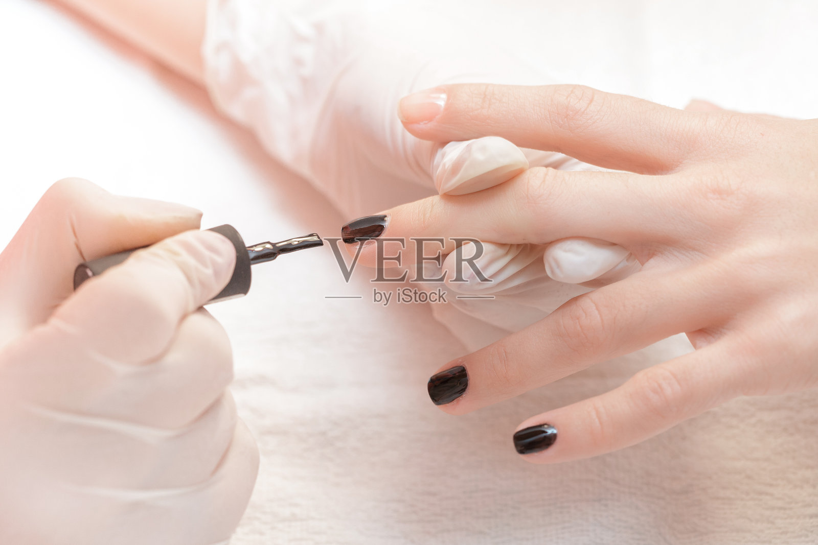 给妇女涂指甲油的美容师照片摄影图片