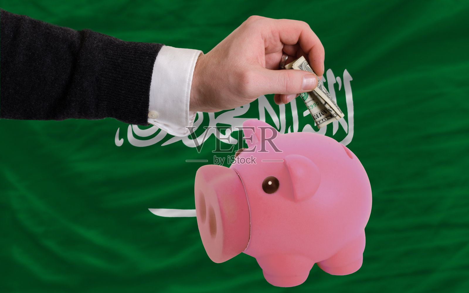 美元进入小猪存钱罐和沙特阿拉伯国旗照片摄影图片