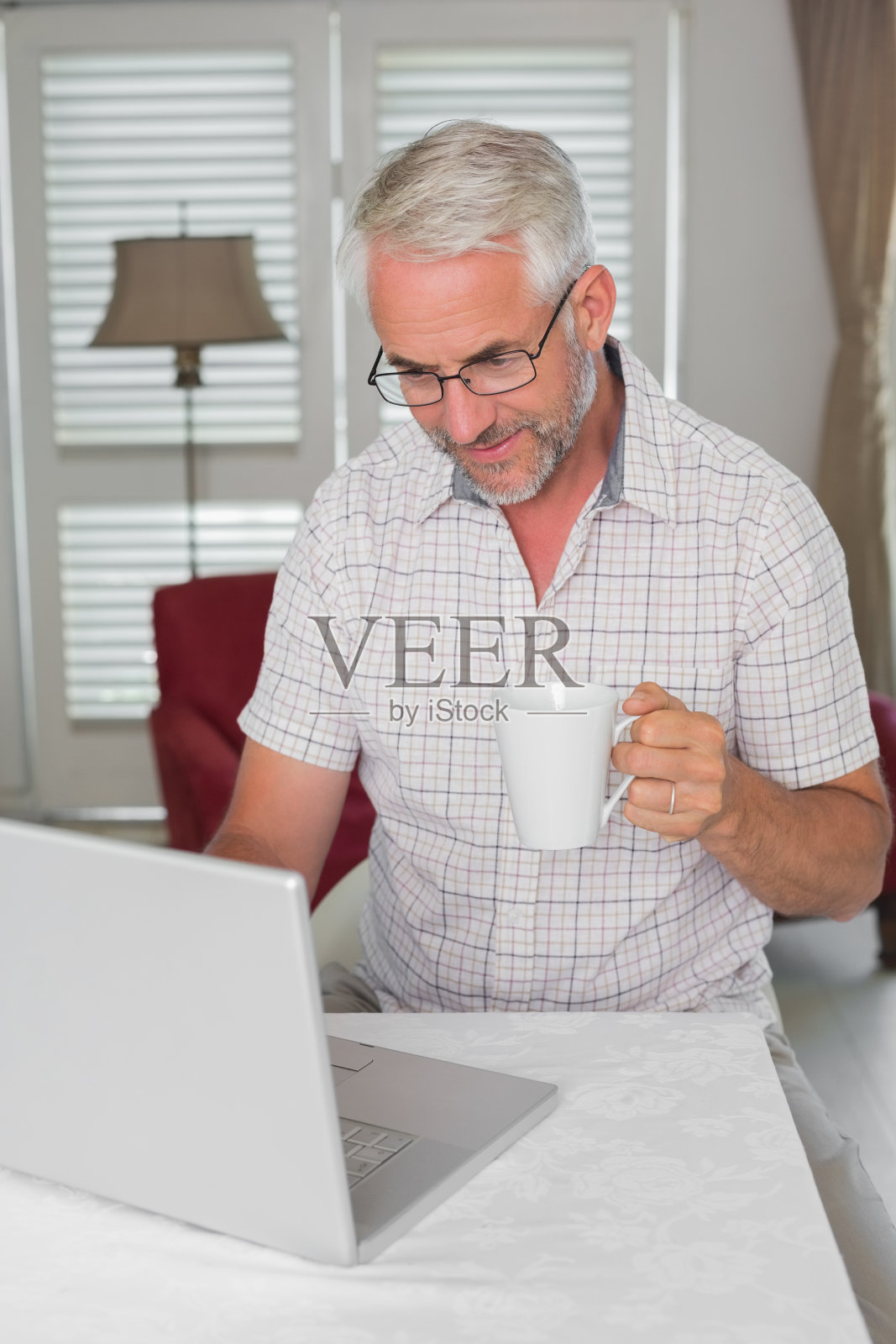 休闲成熟的男人一边喝咖啡一边用笔记本电脑照片摄影图片
