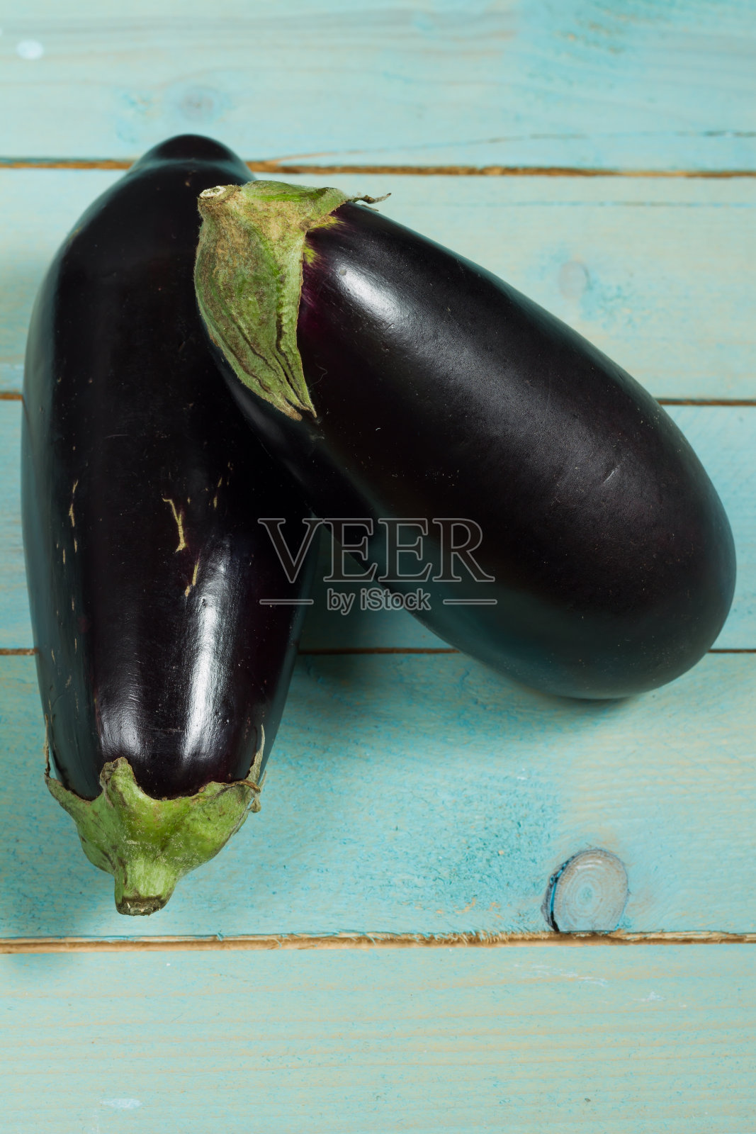 蓝色的木桌上放着茄子。照片摄影图片