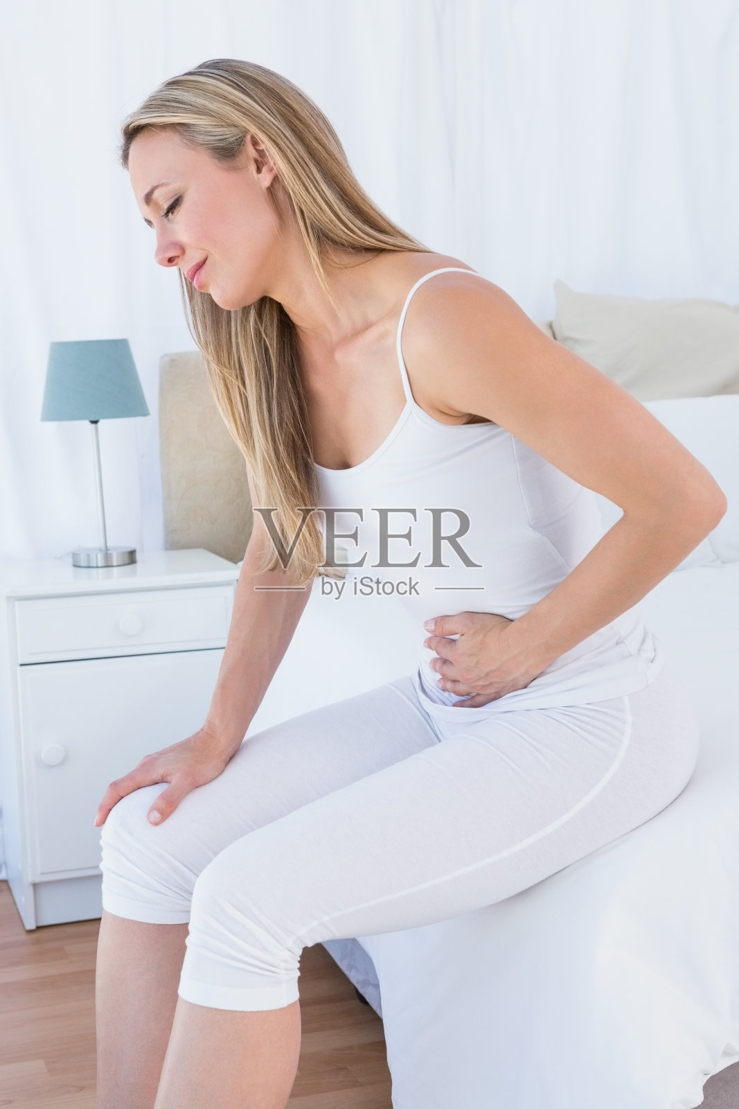 心烦意乱的金发女郎遭受胃痛照片摄影图片