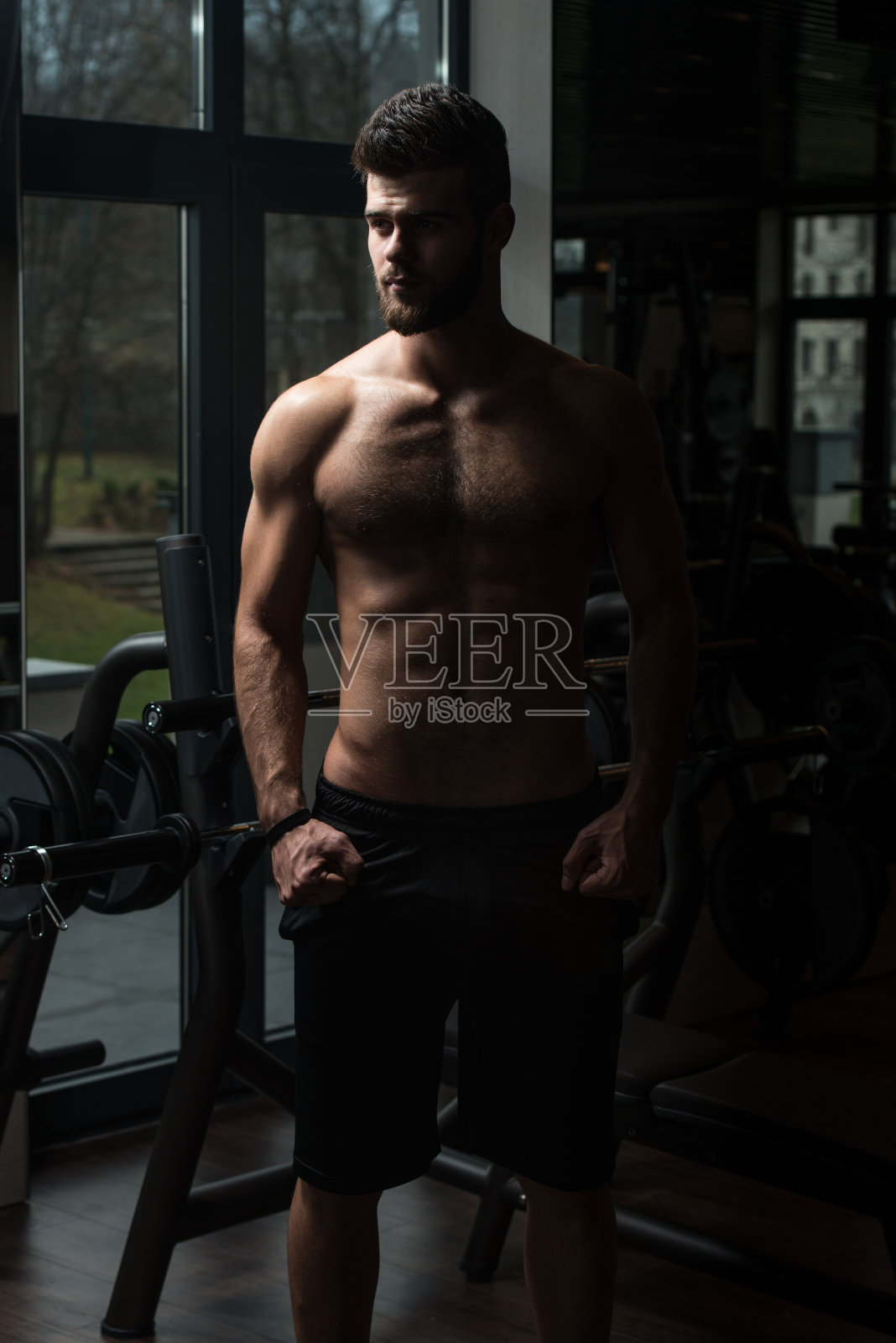 在健身房里摆姿势的年轻英俊男子照片摄影图片