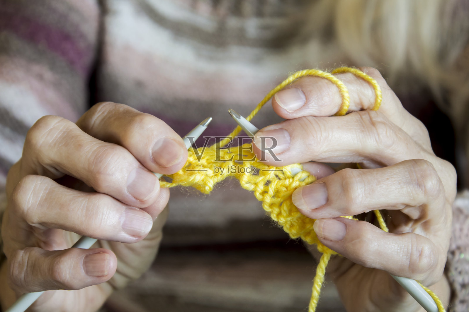 女人的手上拿着编织针和黄线,用来系围巾照片摄影图片