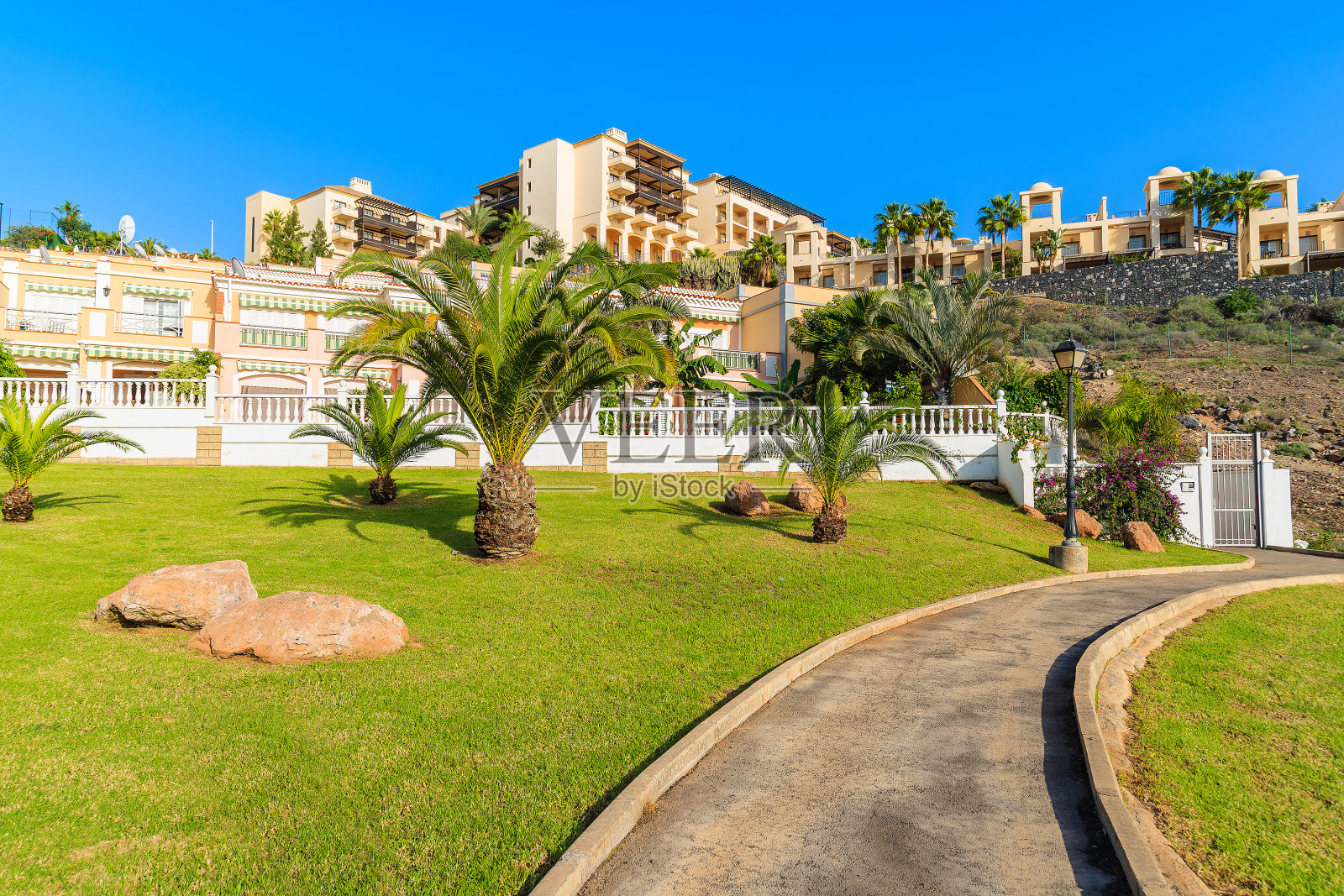 西班牙加那利群岛的特内里费,Costa Adeje镇热带公园的散步小路,背景是度假公寓照片摄影图片