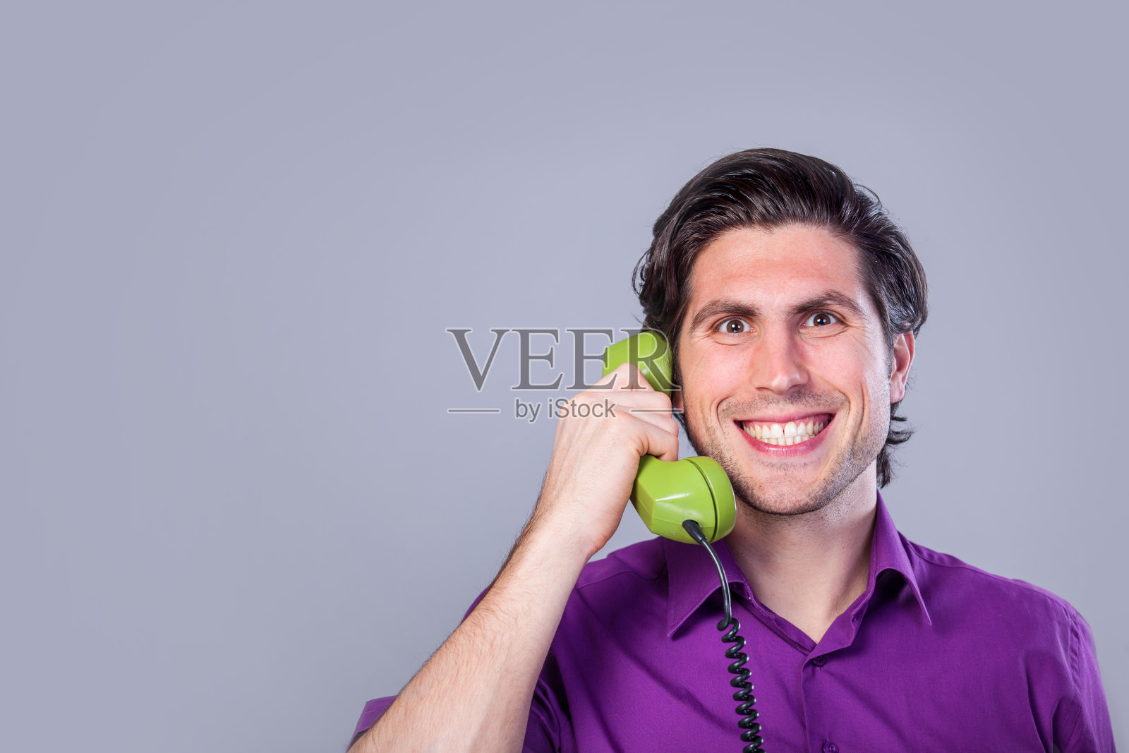 灰色背景上有电话的英俊男子。照片摄影图片