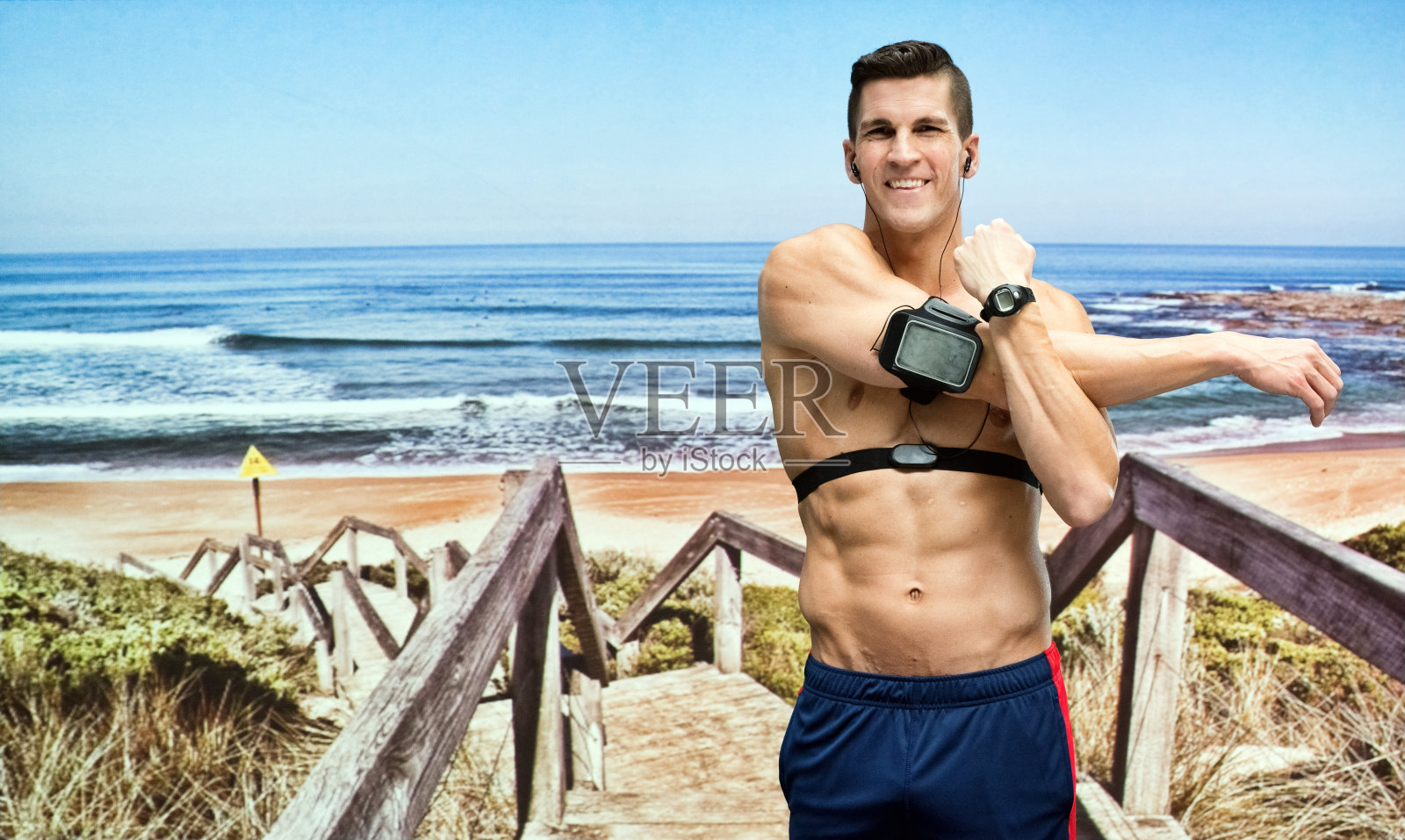 微笑的男性跑步者在海滩伸展照片摄影图片