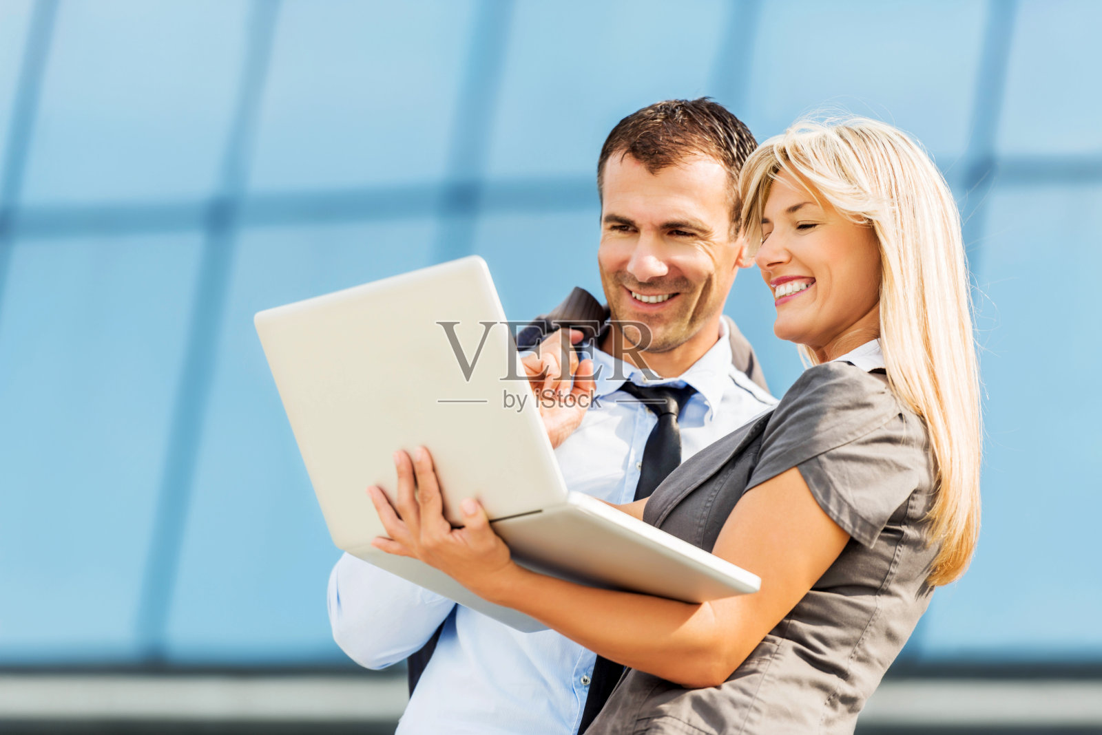 愉快的商务人士在户外使用笔记本电脑。照片摄影图片